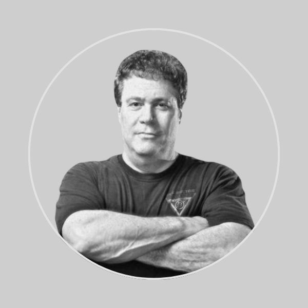 Black and white photo of a man (Darren Levine) with crossed arms, wearing a T-shirt, looking at the camera.