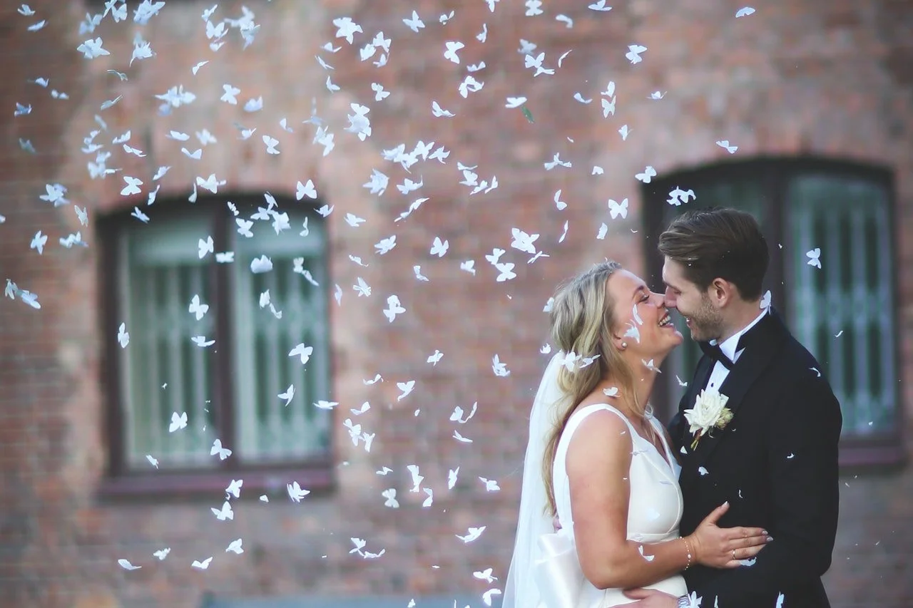 Nylig giftemål med en brud og brudgom som forsøker å kysse hverandre midt i et skur av hvite fugler.