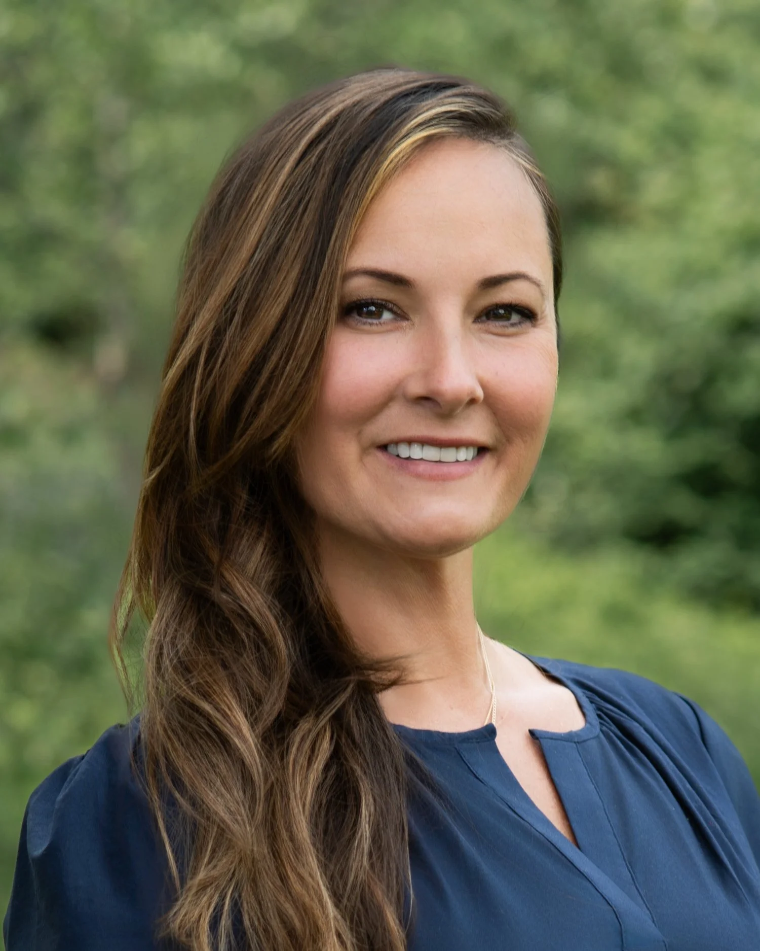 Professional outdoor headshot of woman with natural green background