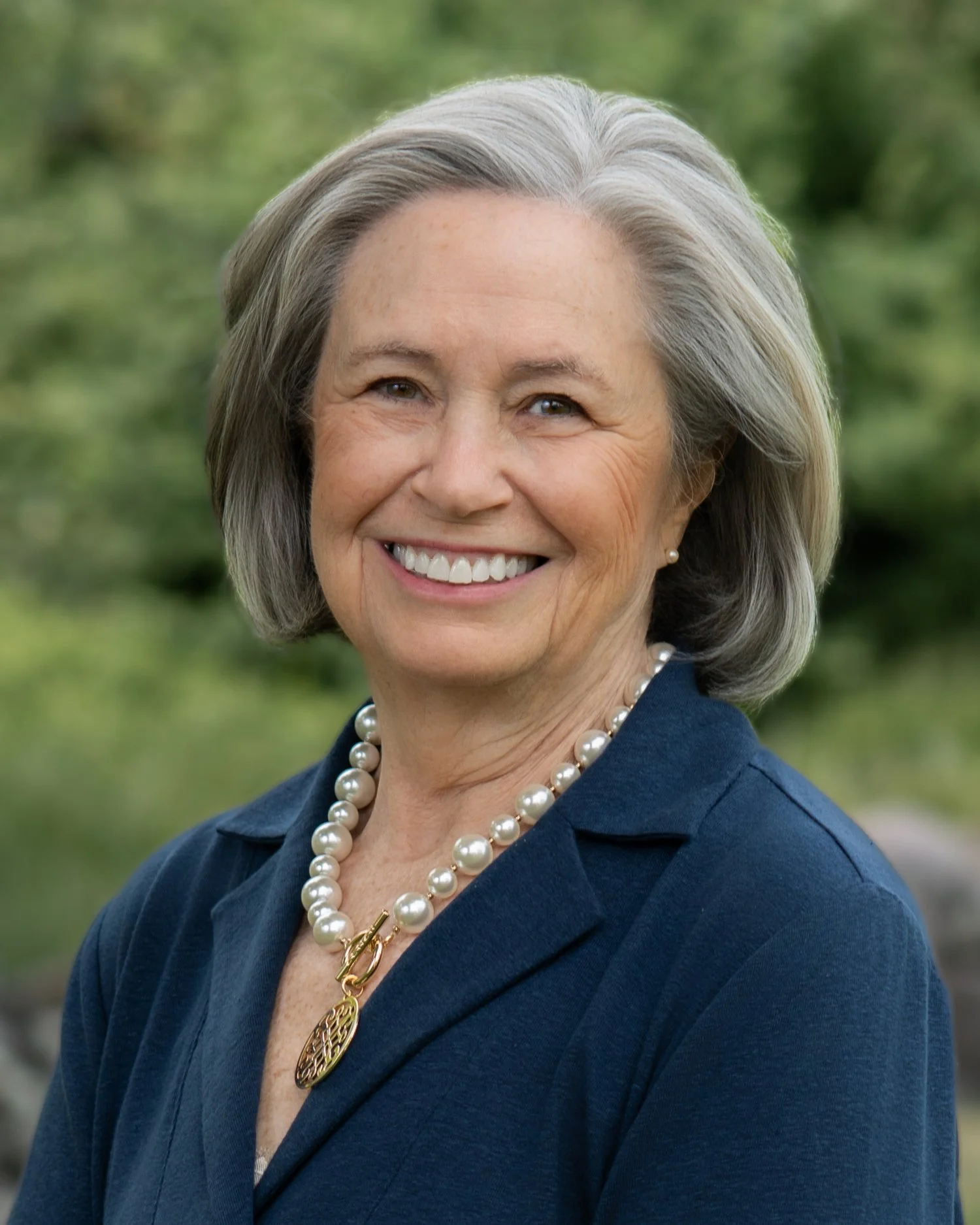 Professional outdoor headshot of woman with natural green background