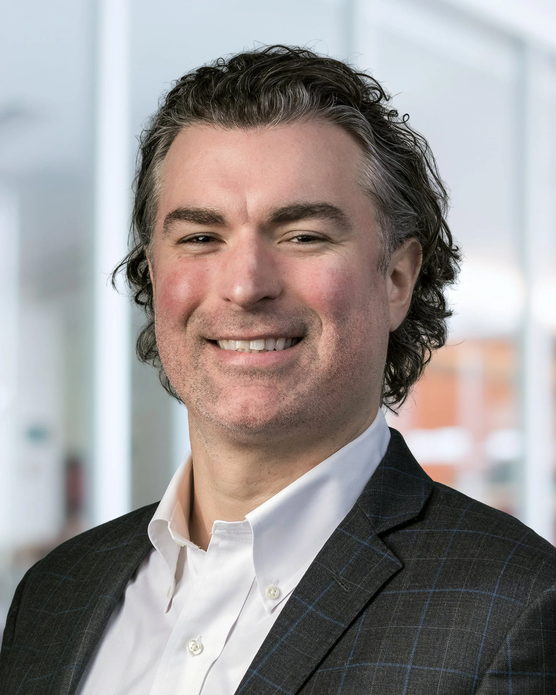 Headshot of a professional man taken indoors with blurred office background