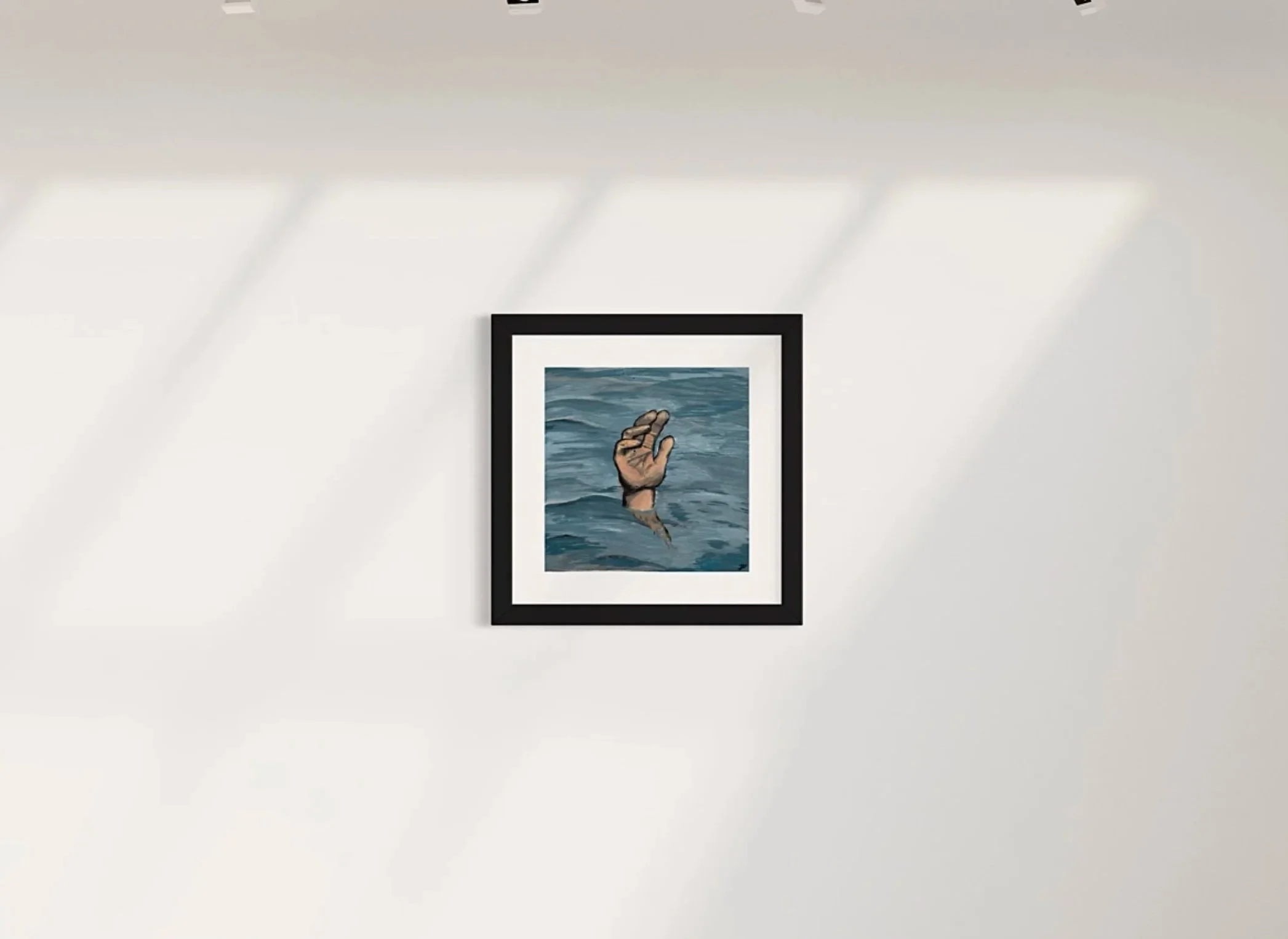 Framed artwork of a hand reaching out of the water on a white gallery wall.