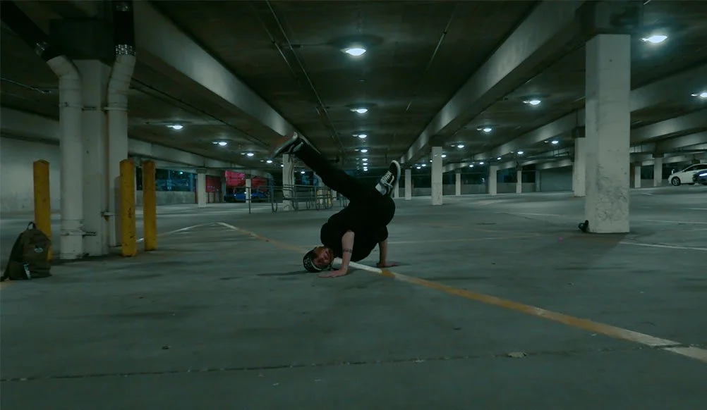 Person performing a handstand in an empty parking garage at night.