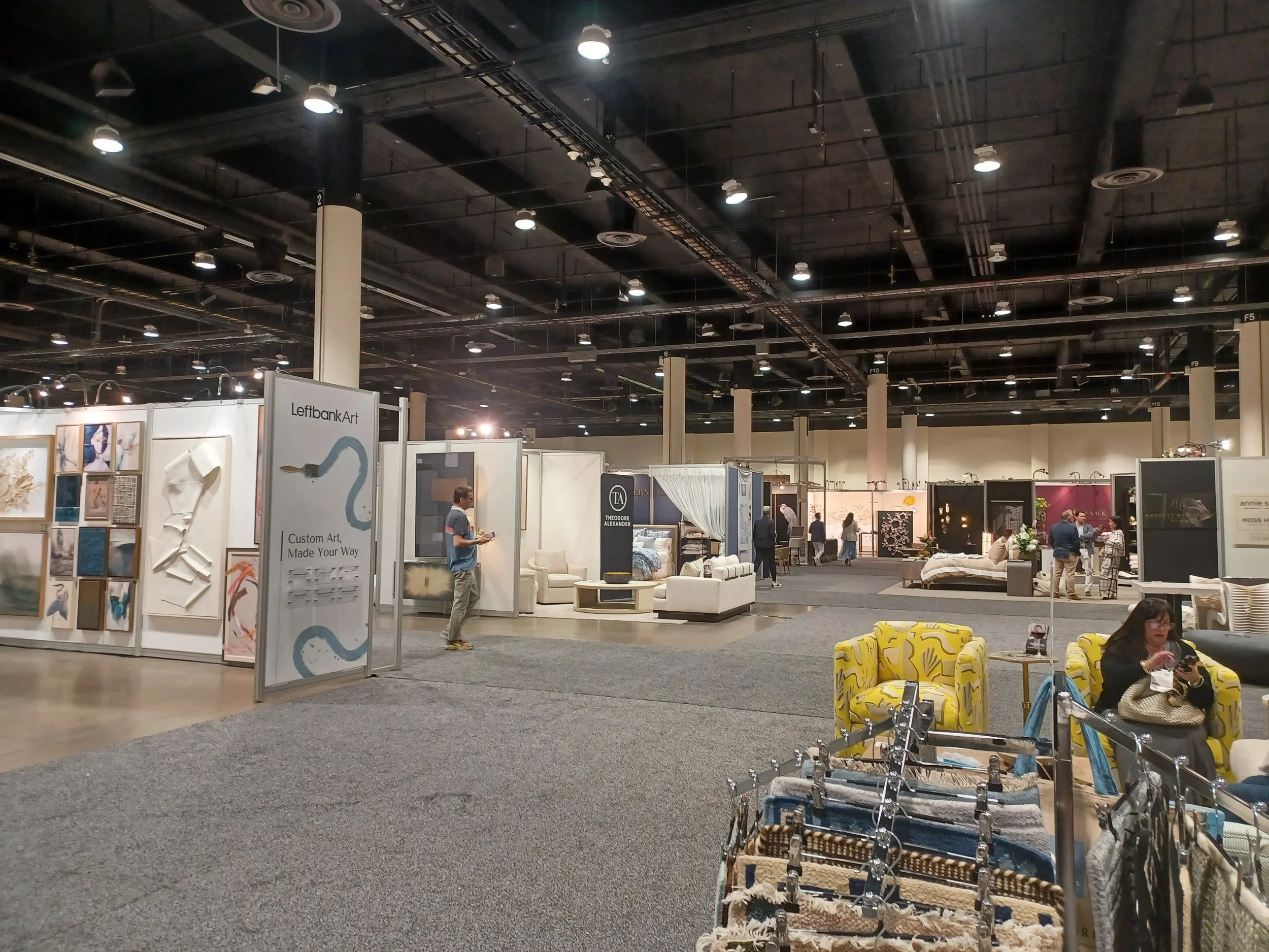trade show hall in orlando with multiple booths of furniture and art
