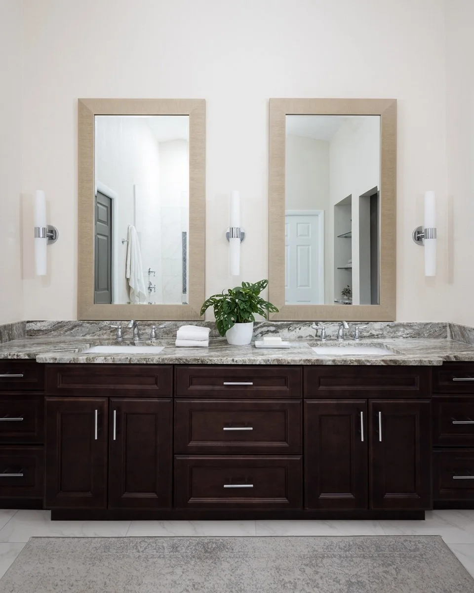 Primanry bahroom vanity with a highly veined granite countertop, large mirrors, and white accessories in Tampa Bay, FL.