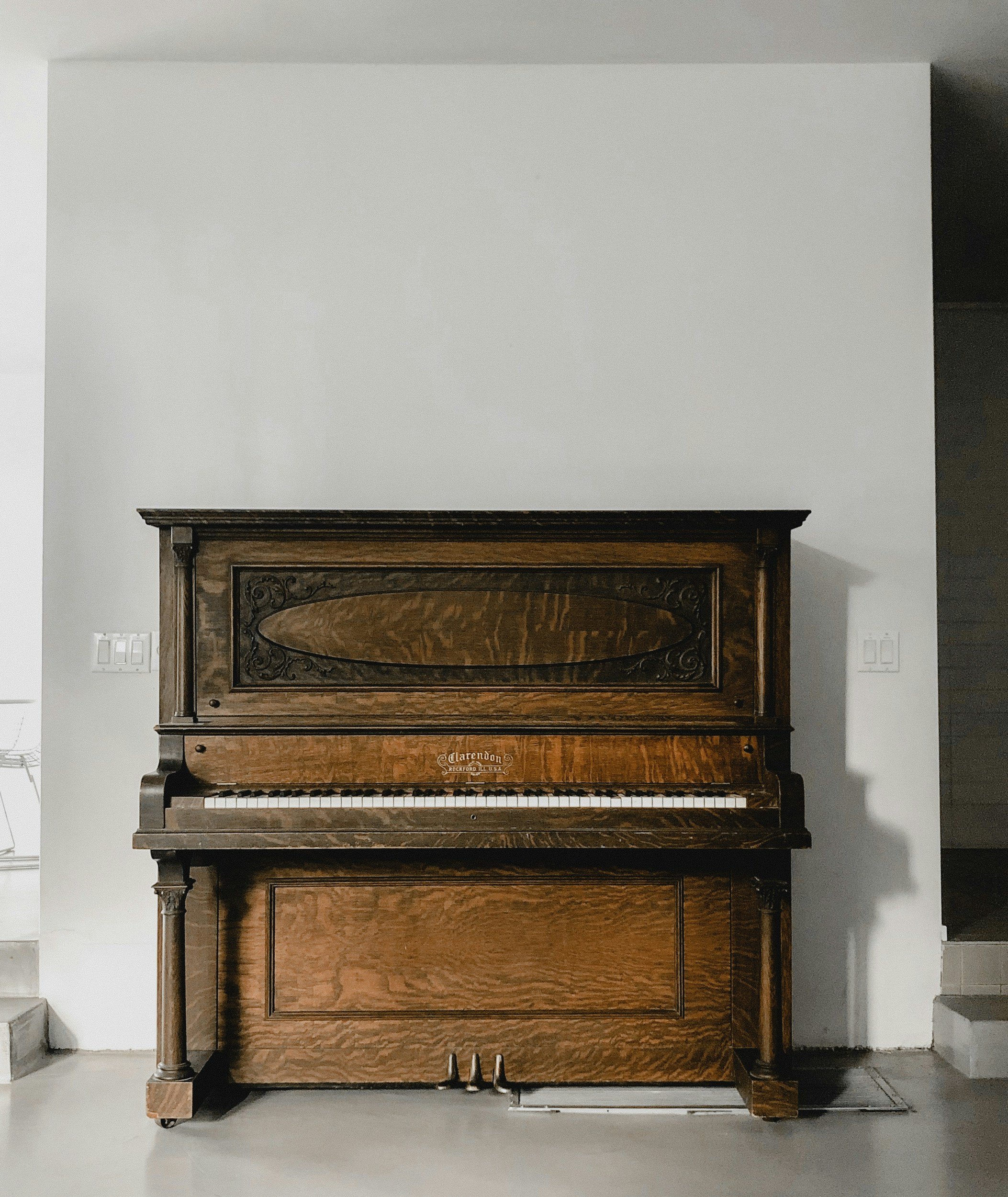 A vintage upright piano with a dark wood finish, placed against a white wall in a modern room, we had to move this from a local restaurant to the owners home.