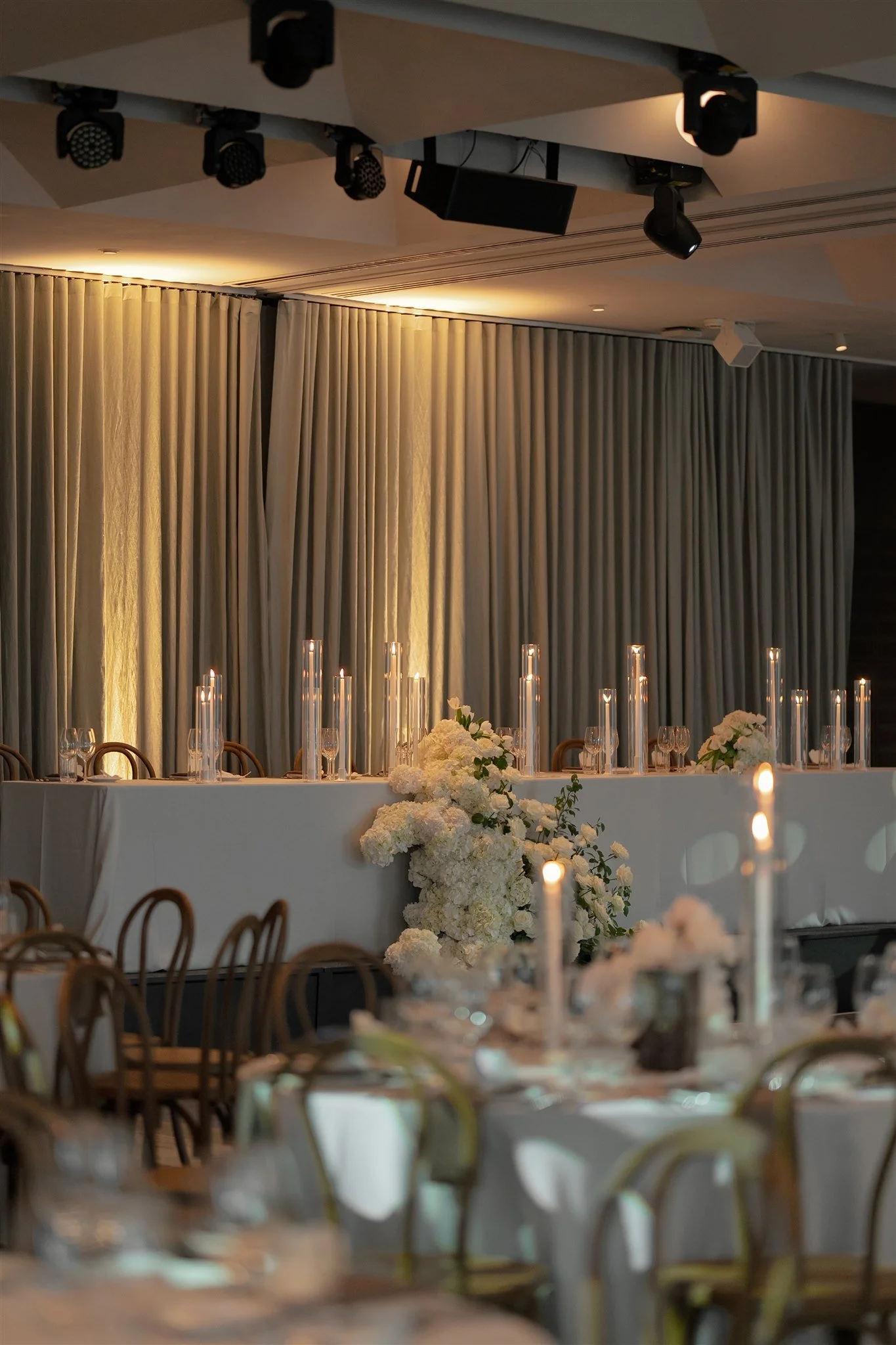 Traditional Bridal Head Table - modern romantic styling featuring pebble weave textured tablecloth, tall dinner candles in sleeves, walnut chairs, and cascading florals in neutral tones of cream, browns and gree.ns - styling by Philoxi Styling.