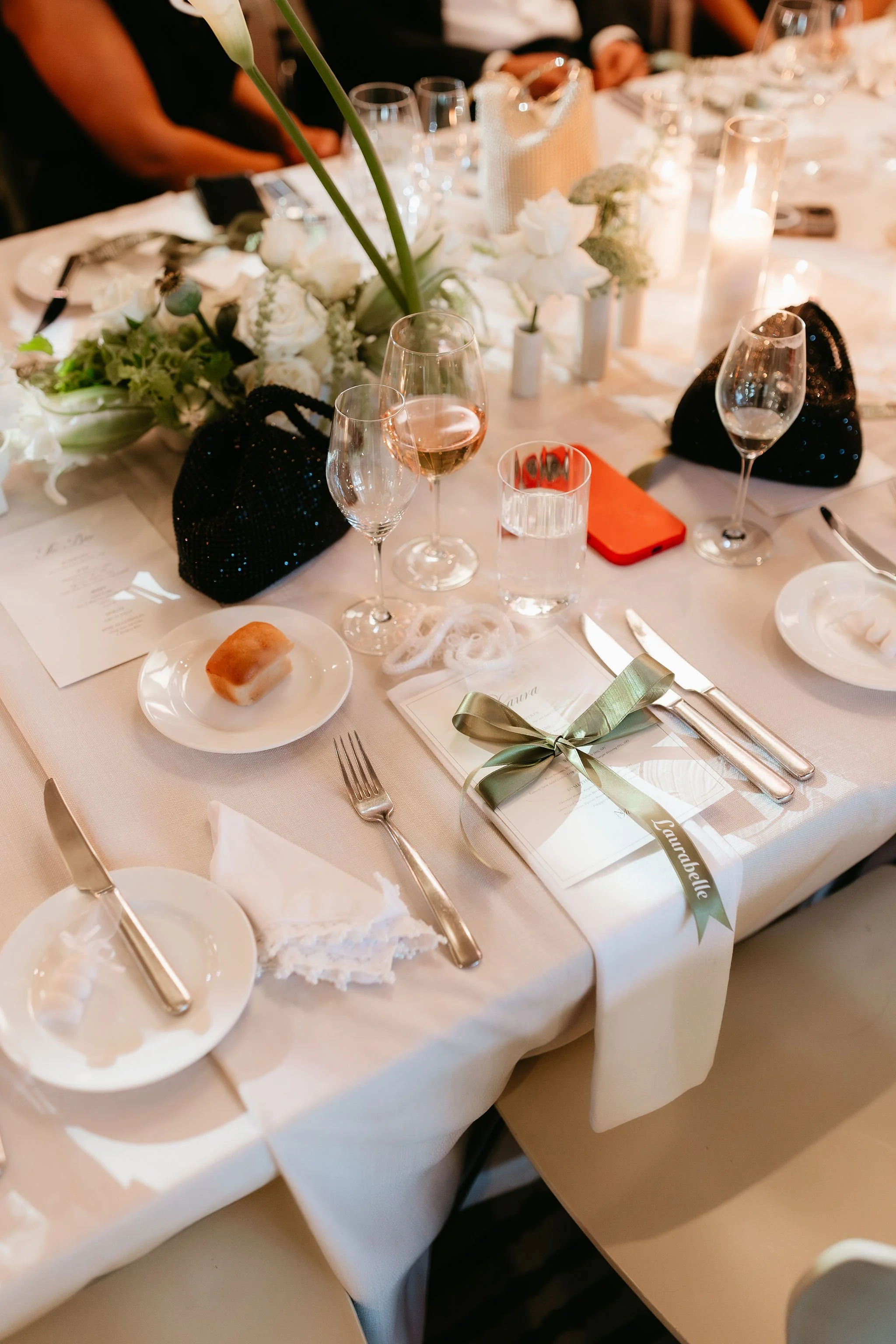 Elegant women's evening bags, iphone's on table. Wedding guests seated ready for entree. Sophisticated, luxe table centrepieces by Melbourne wedding florist, Judah Rose. Photography: Miranda Stokkel. 
