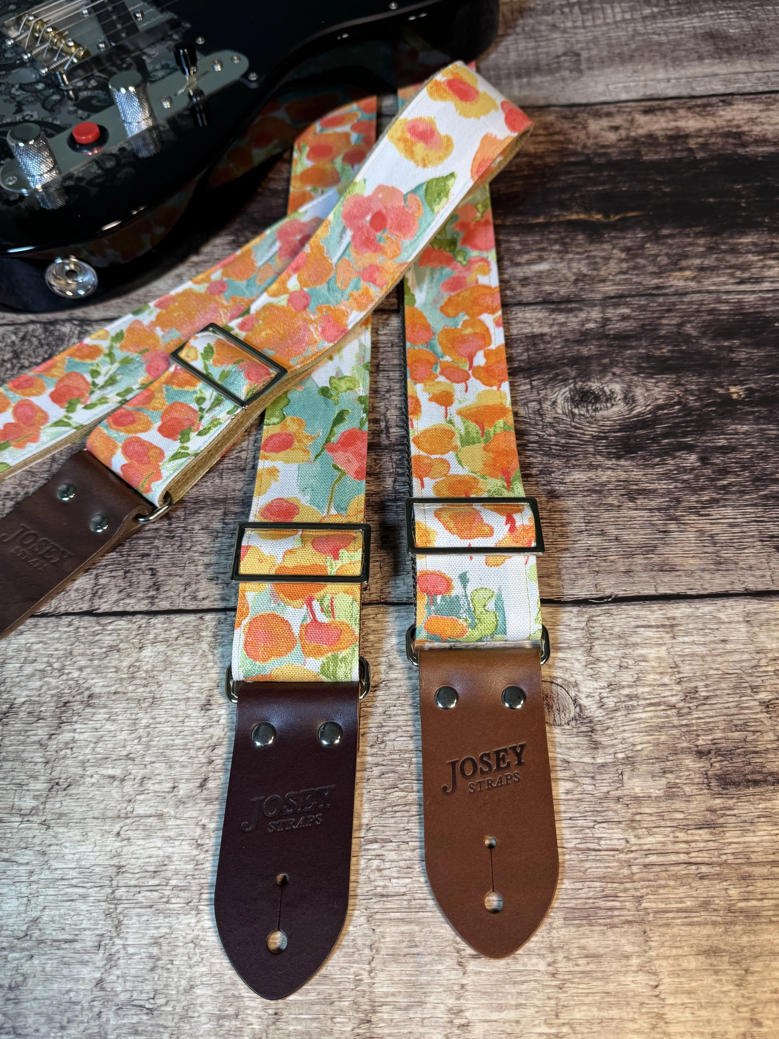 Floral guitar straps with orange, gold, and green flower pattern and leather ends by Josey Straps, In Bloom design
