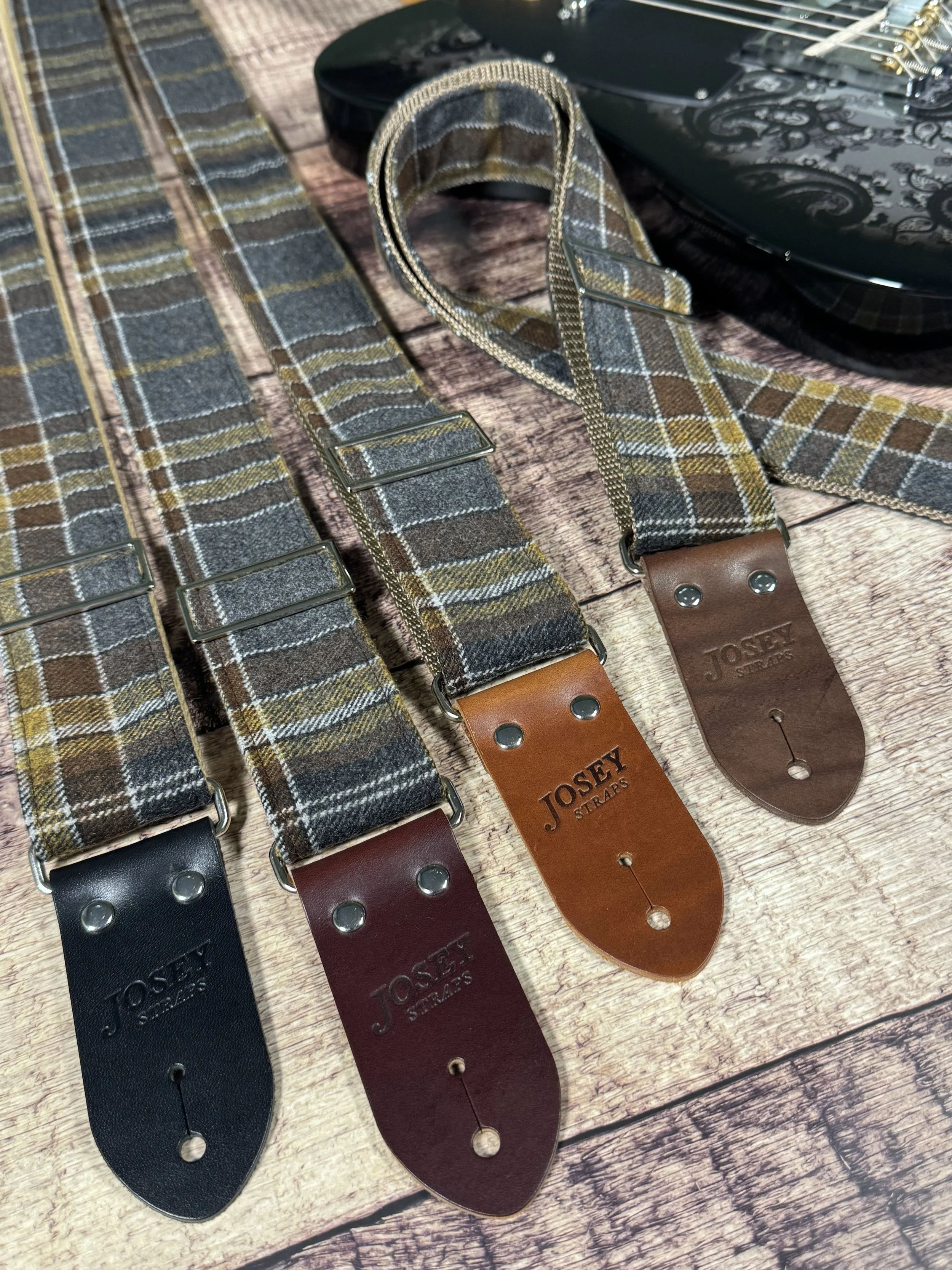 Ashes plaid guitar strap with leather ends by Josey Straps displayed on wood background