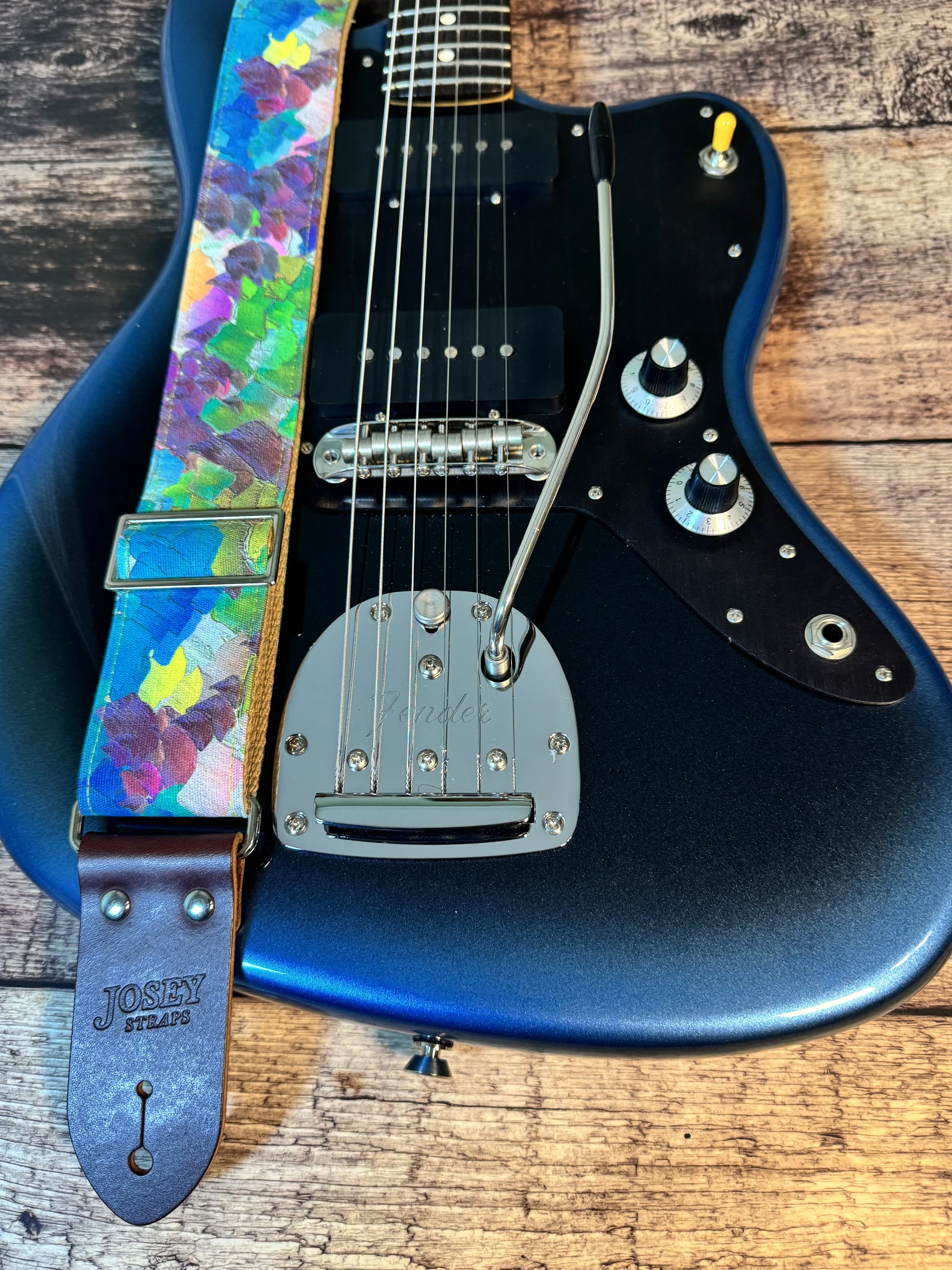 Impasto handmade guitar strap by Josey Straps featuring a vibrant abstract painterly pattern in blue, green, purple, and yellow with premium leather ends.