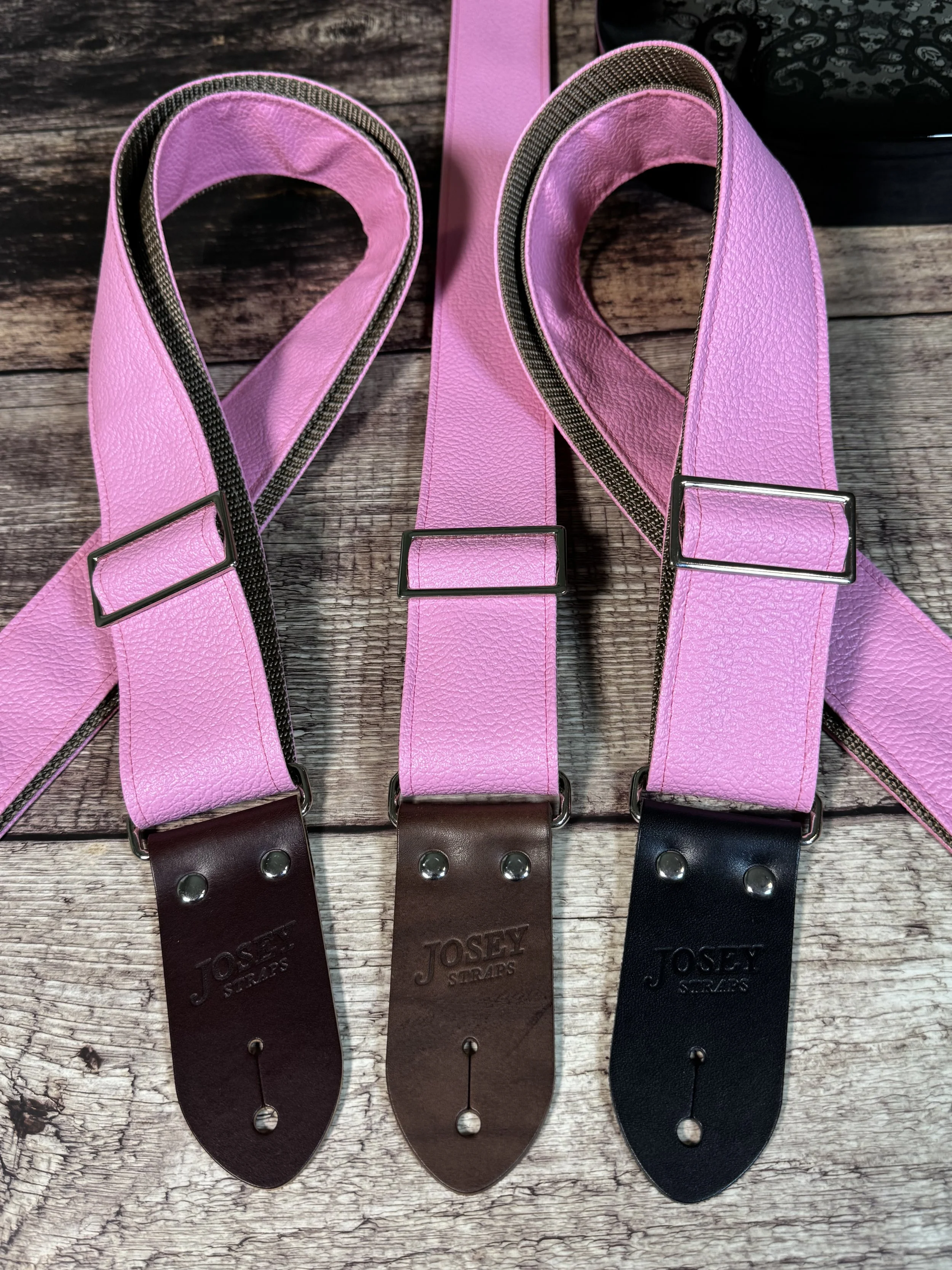 Bubblegum pink tolex guitar straps on wooden floor.