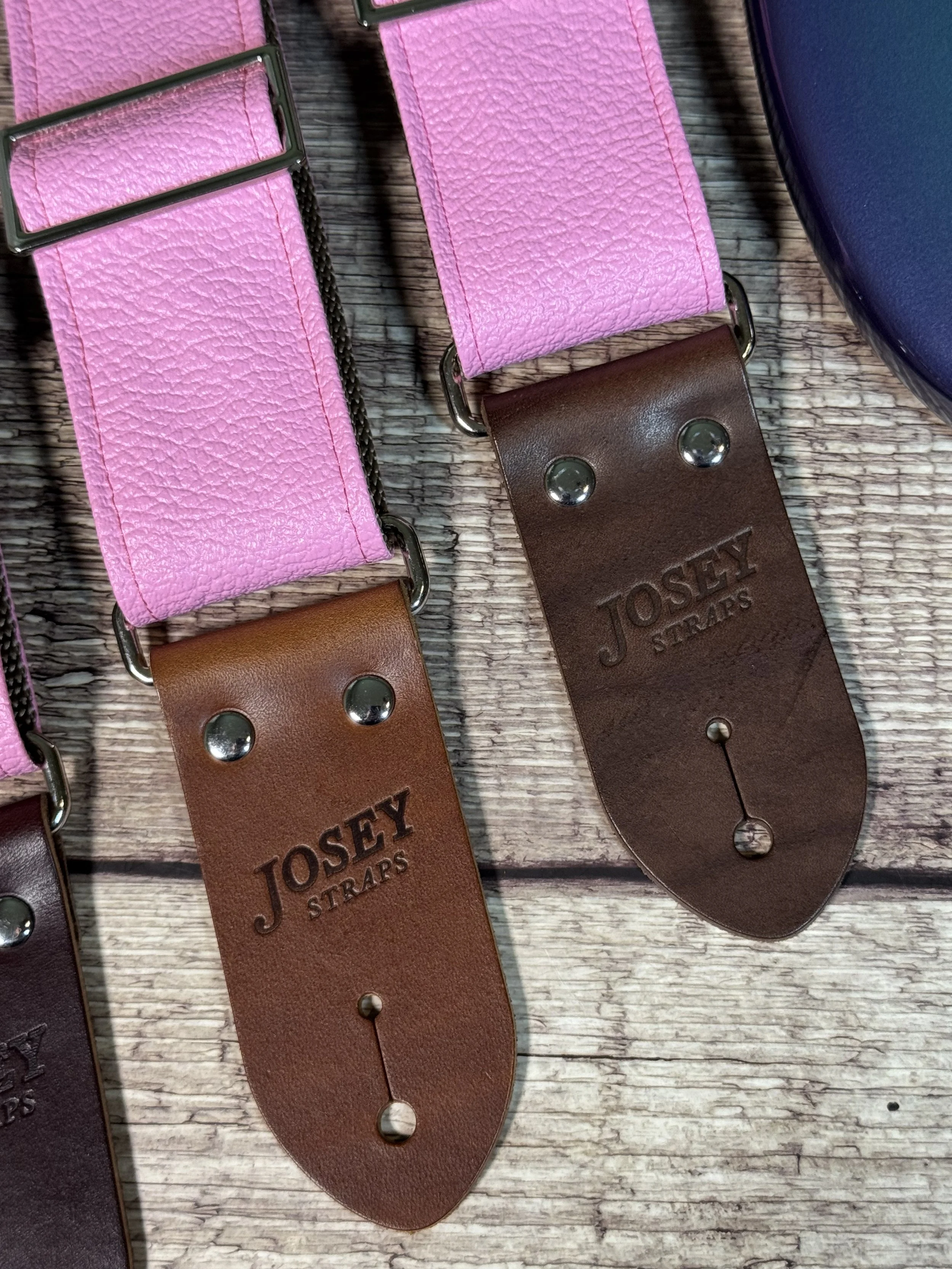 Up close shot of Bubblegum pink tolex guitar straps on wooden floor.