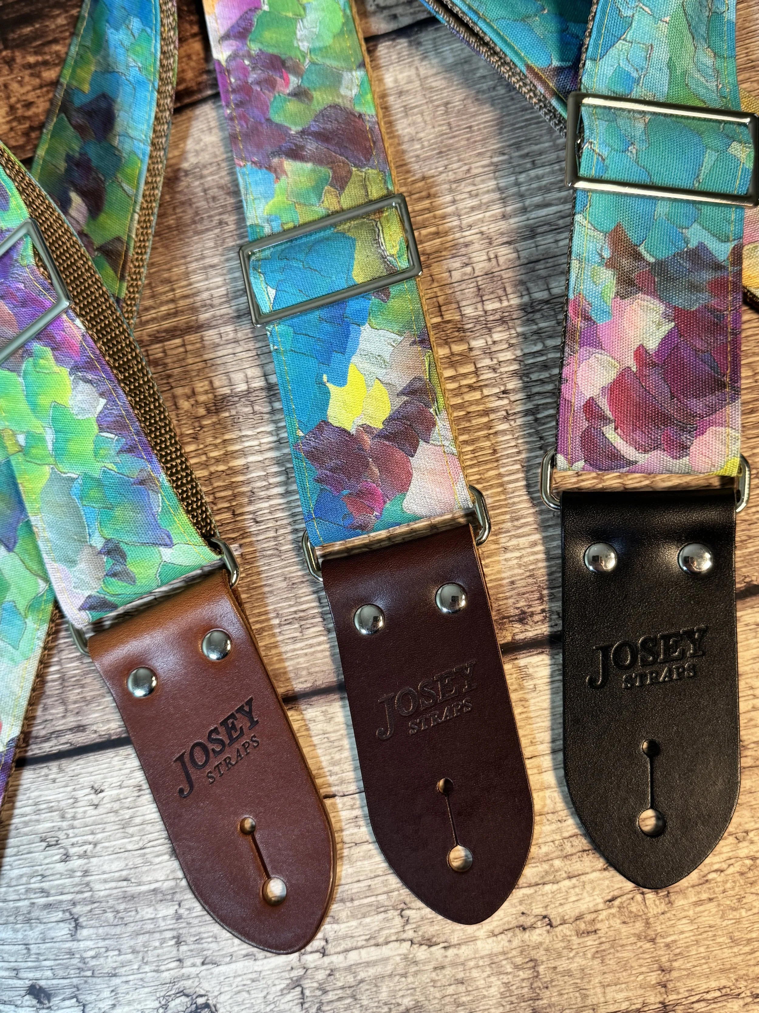 Impasto handmade guitar strap by Josey Straps featuring a vibrant abstract painterly pattern in blue, green, purple, and yellow with premium leather ends.