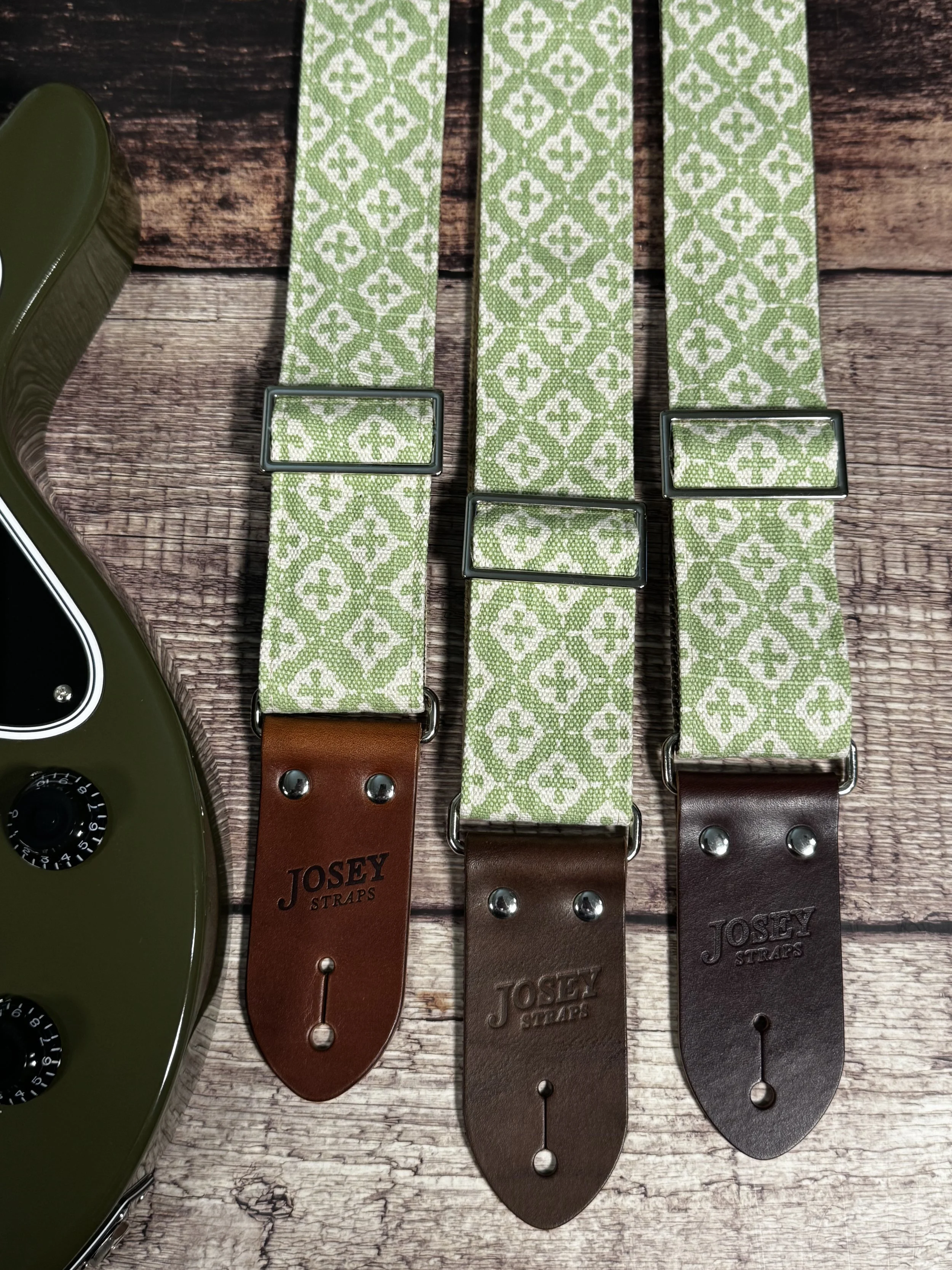 The Green House handmade guitar strap by Josey Straps featuring a sage green and cream geometric pattern with premium leather ends.