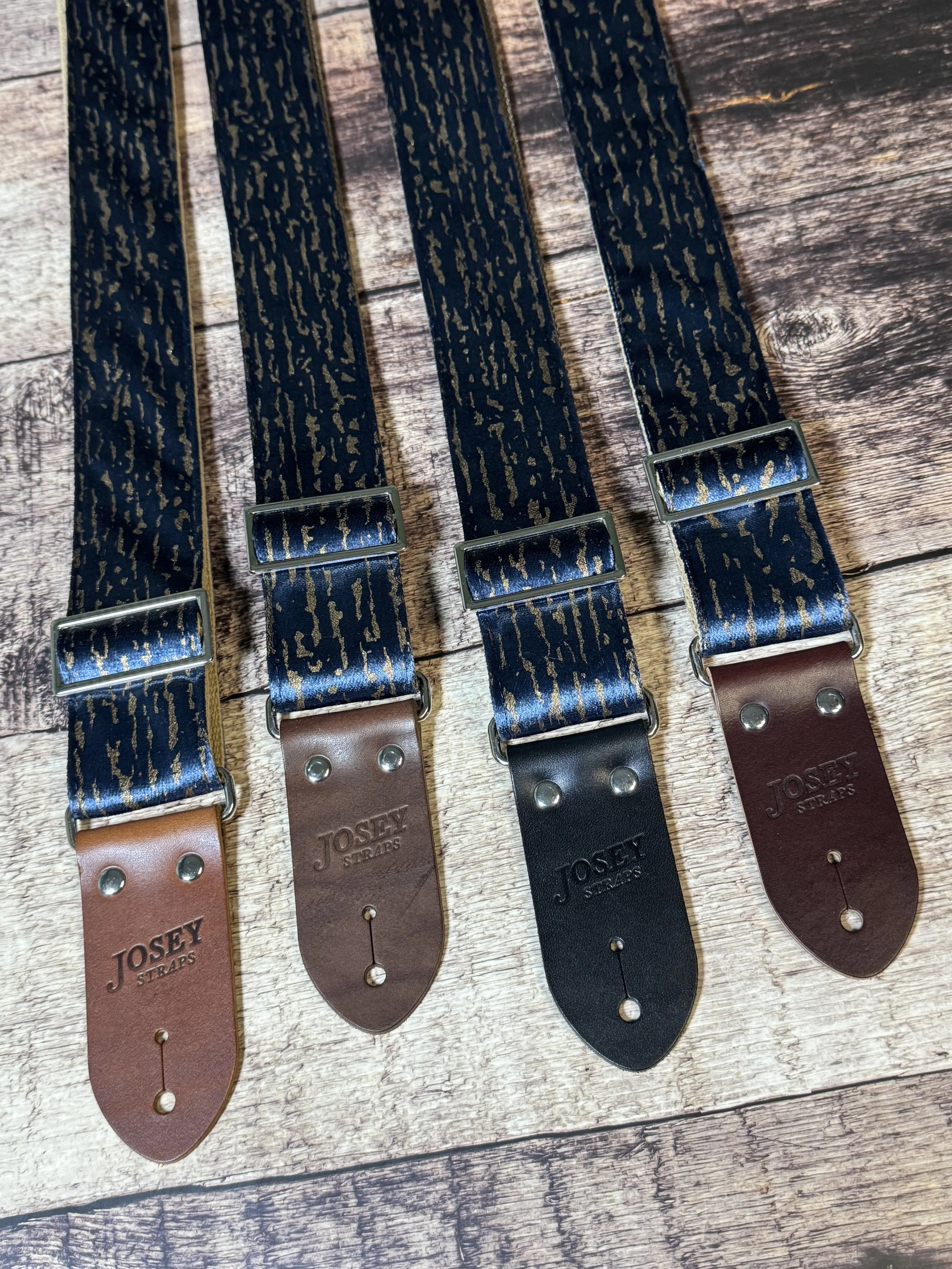 Blue and gold guitar straps on a wooden floor backdrop.