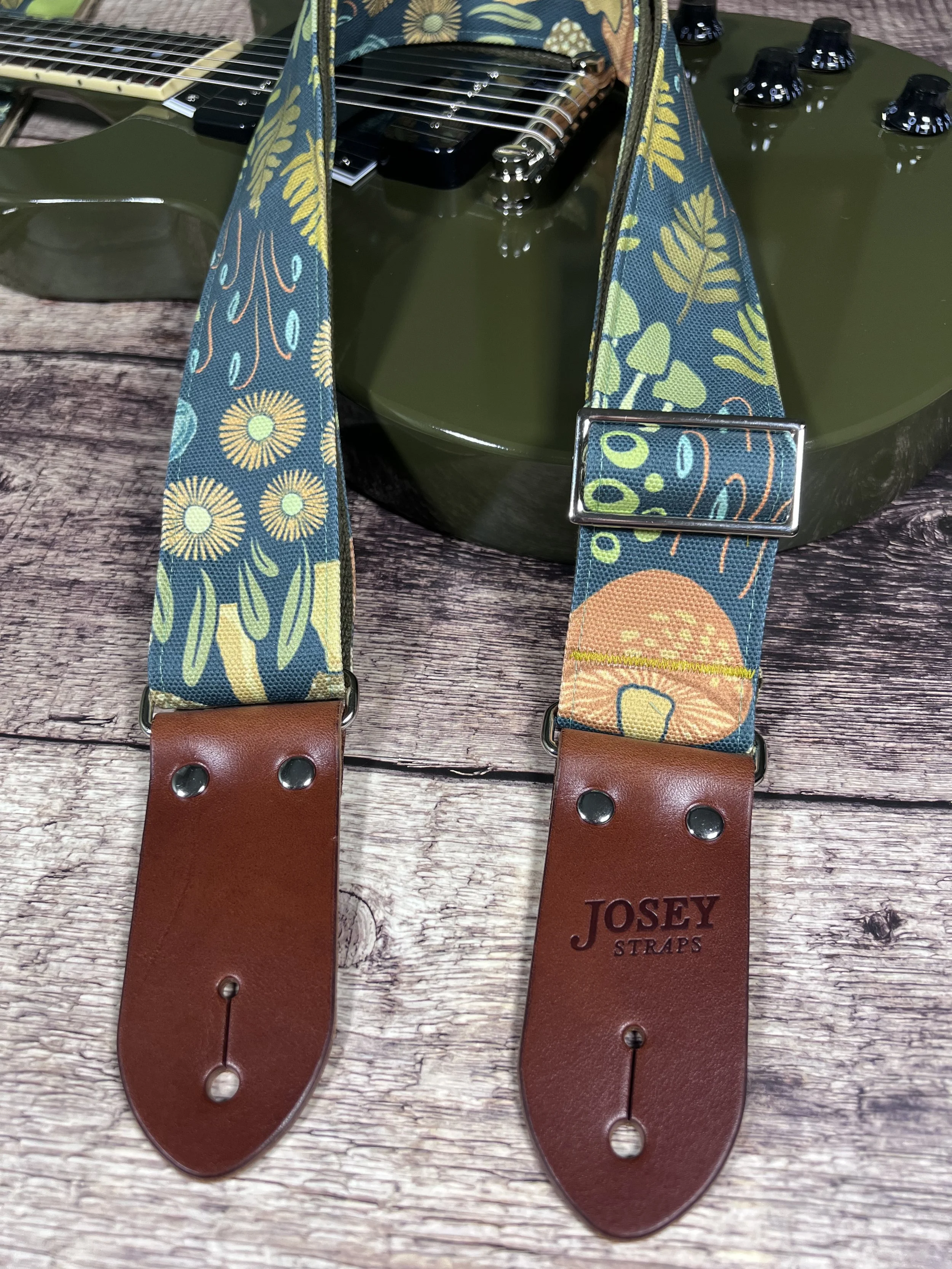 Dark botanical guitar straps on olive green guitar.
