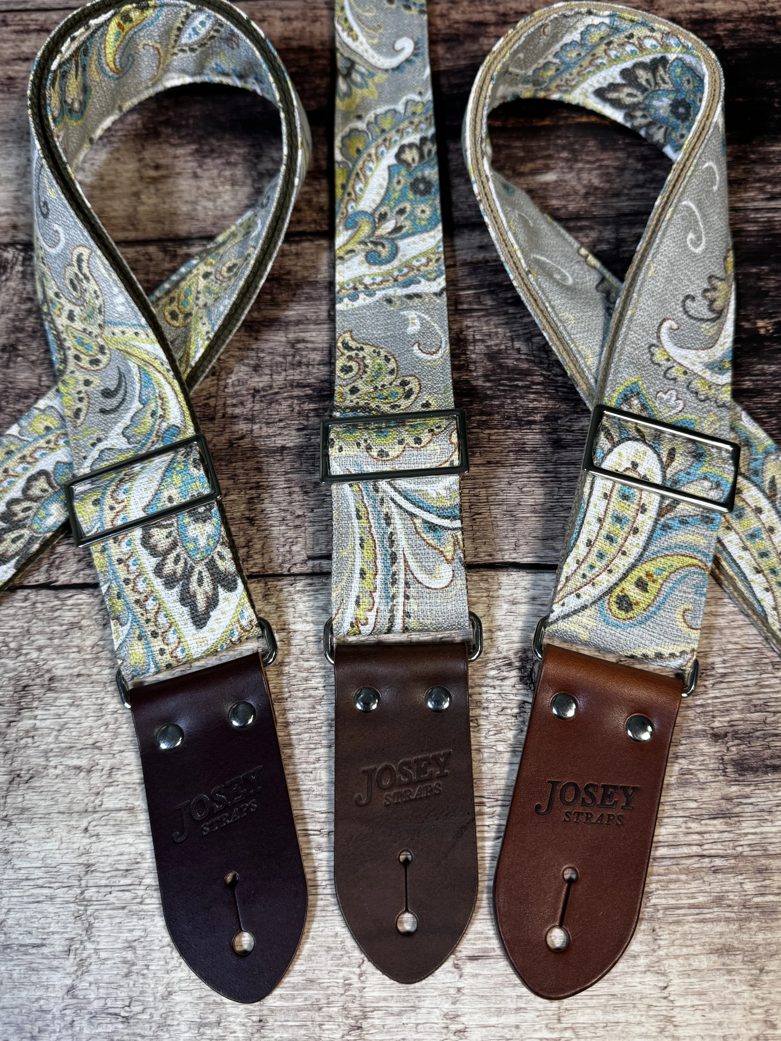Graisley handmade paisley guitar strap featuring a gray, cream, blue, and mustard vintage-inspired pattern with premium leather ends.