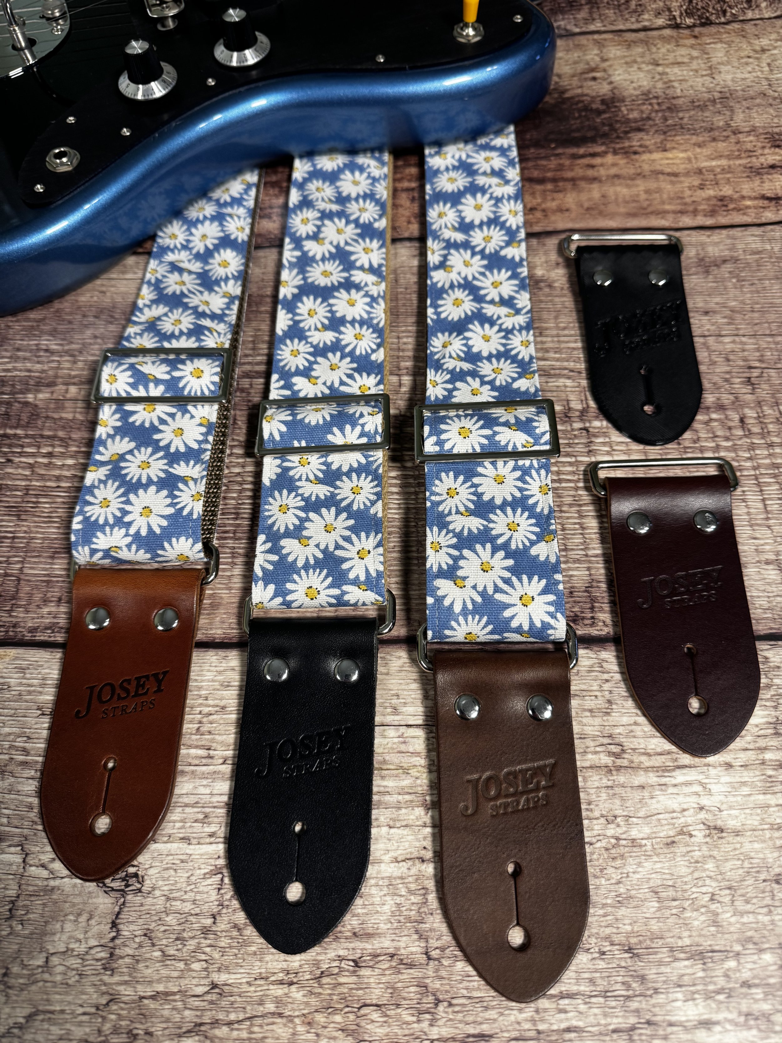 Daisy handmade floral guitar strap by Josey Straps featuring white daisies with yellow centers on a denim-blue background and premium leather ends.
