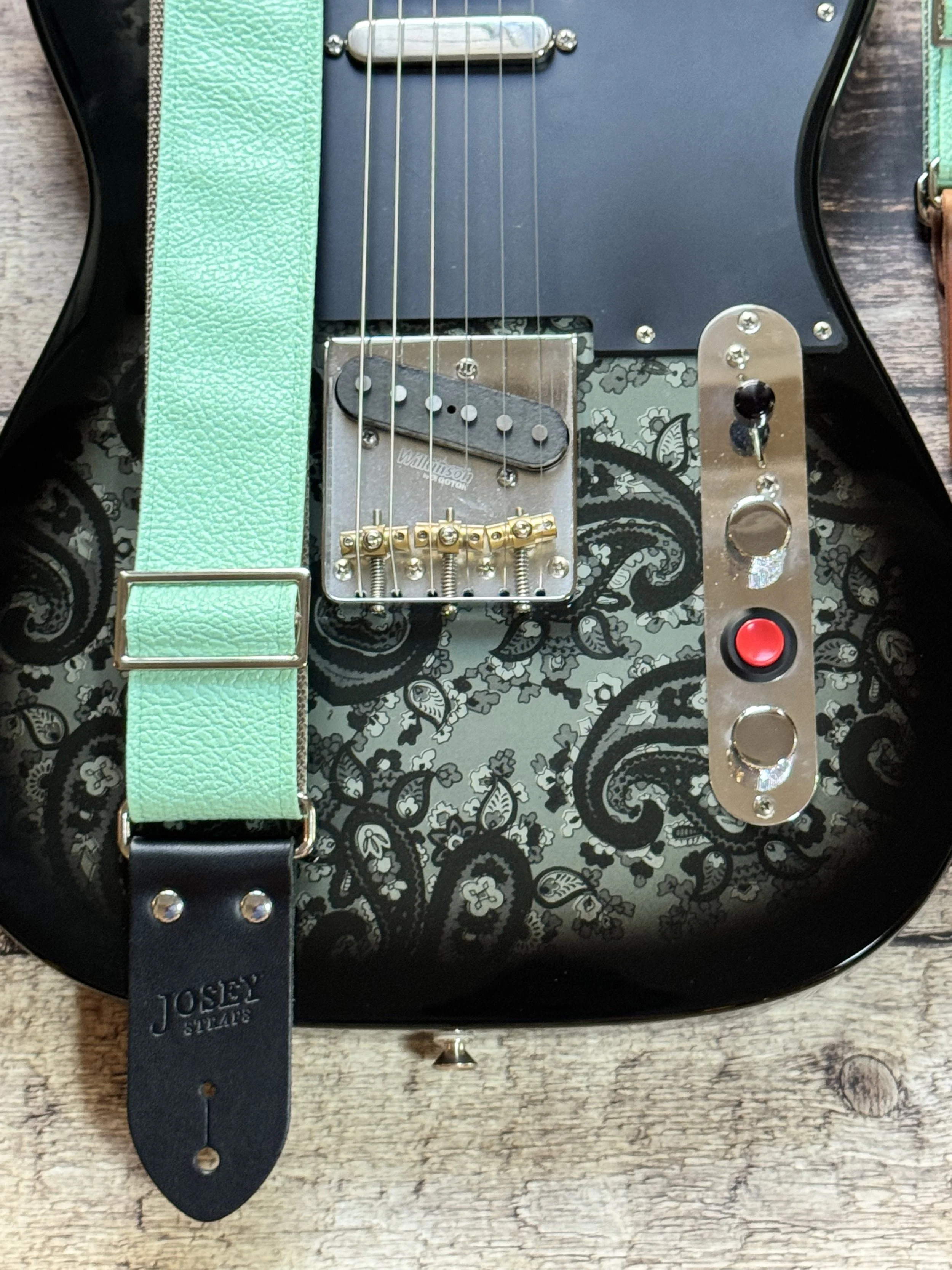 Seafoam green guitar strap on black guitar.
