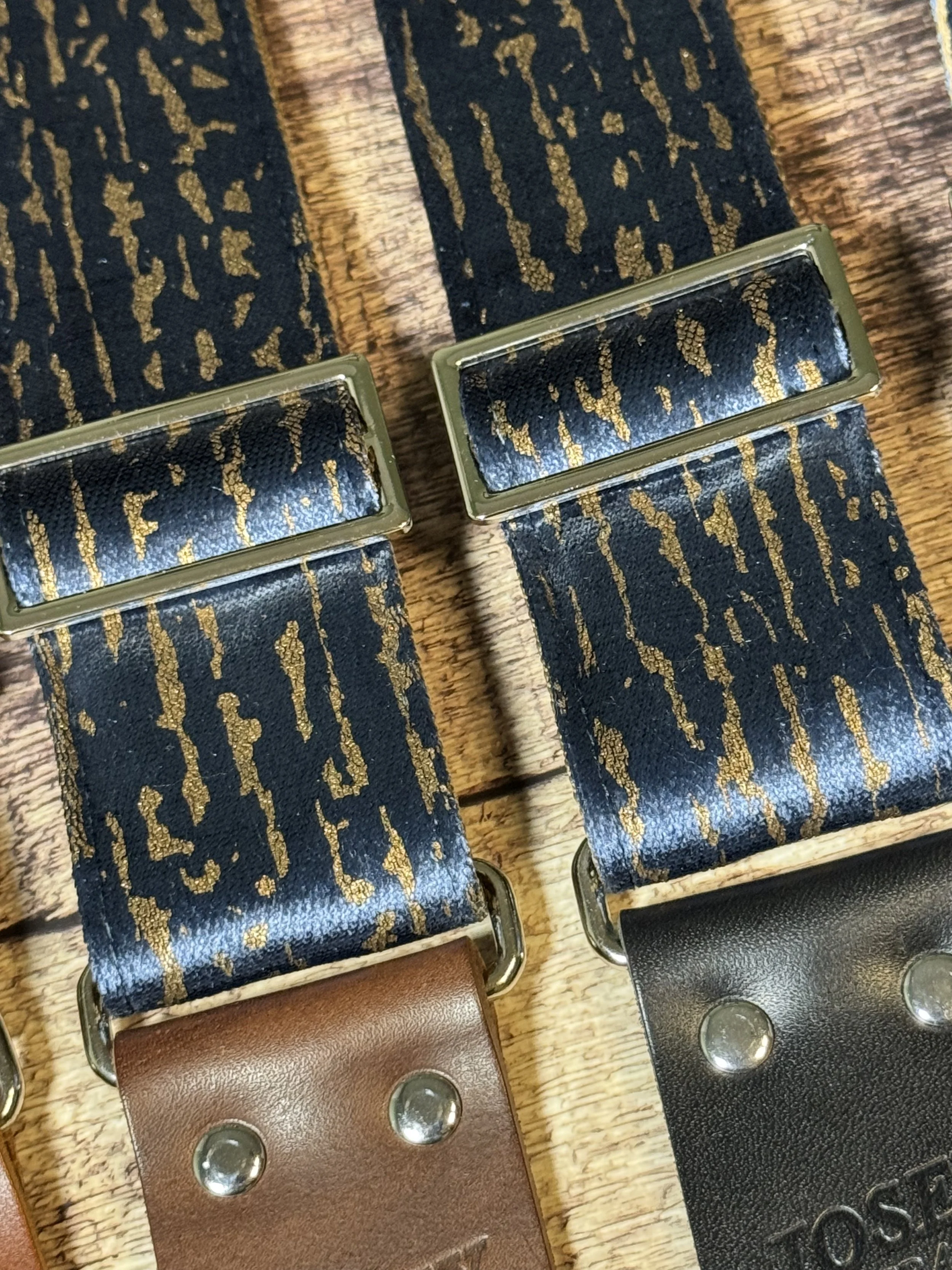 Close up shot of blue and gold guitar straps on a wooden floor backdrop.
