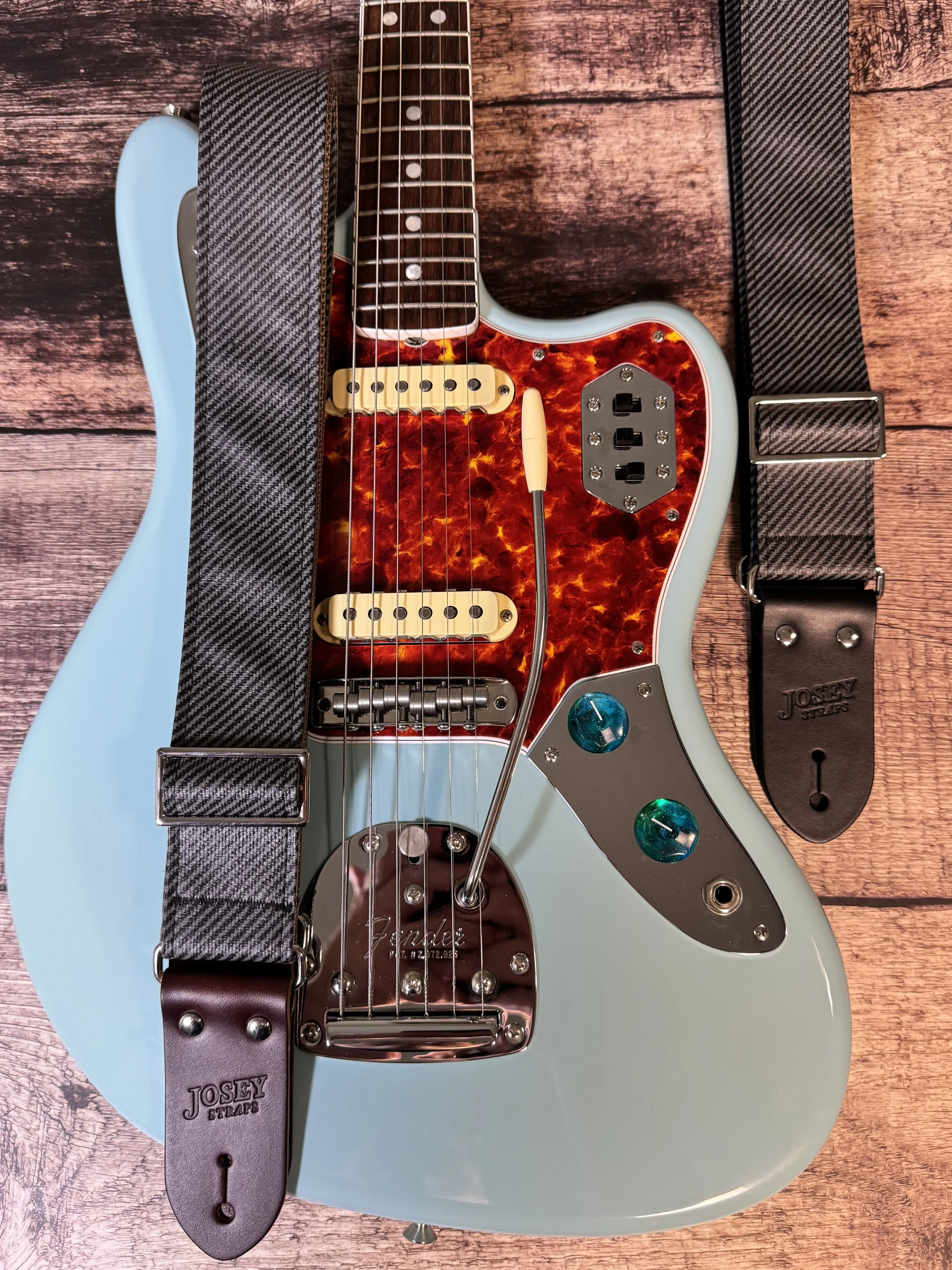 Charcoal tweed guitar straps on blue guitar.
