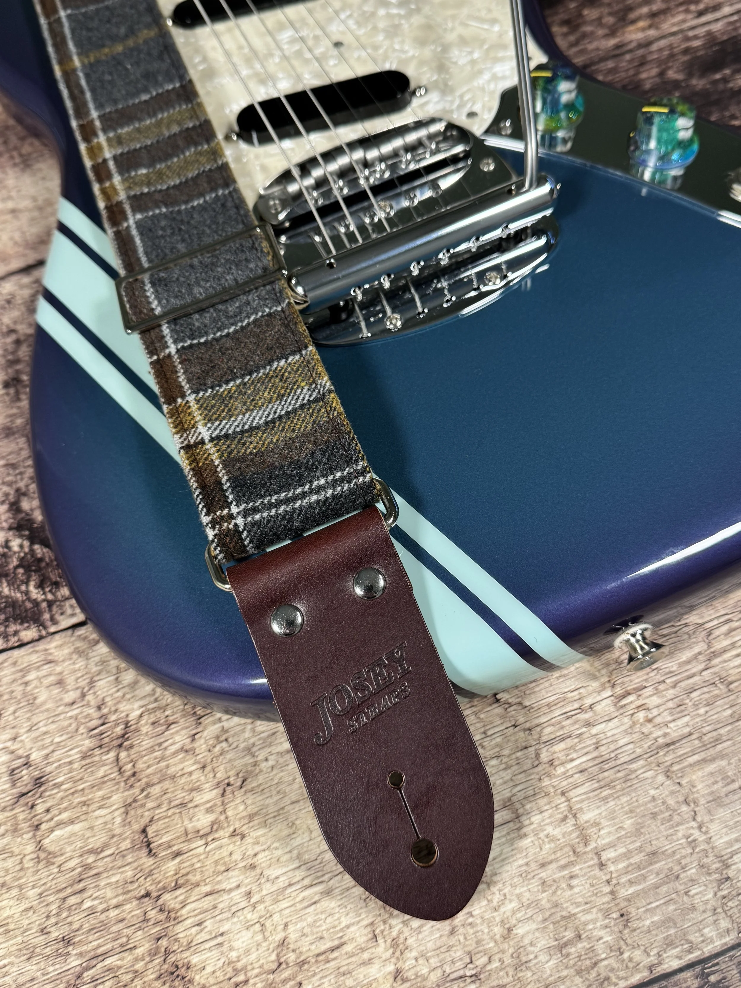 Ashes plaid guitar strap with leather ends by Josey Straps displayed on wood background