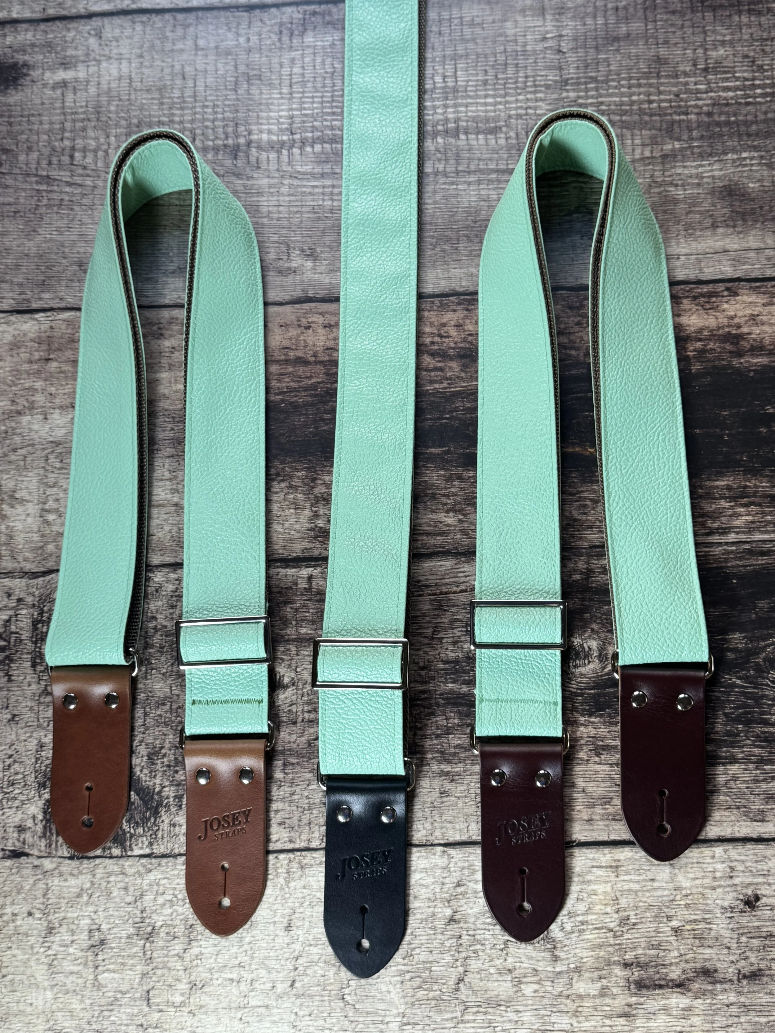 Seafoam green guitar straps on wooden floor.