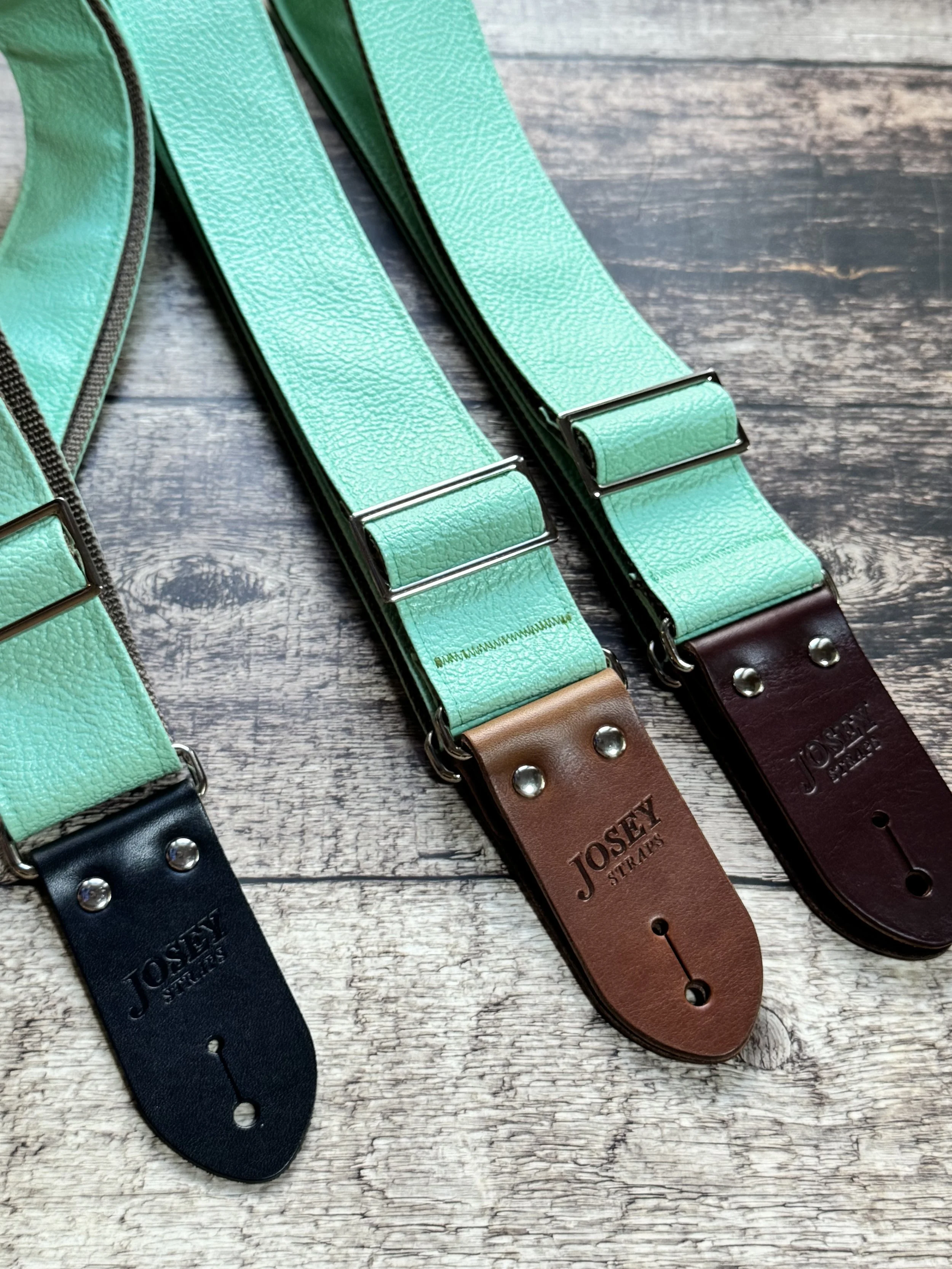 Seafoam green guitar straps on wooden floor.