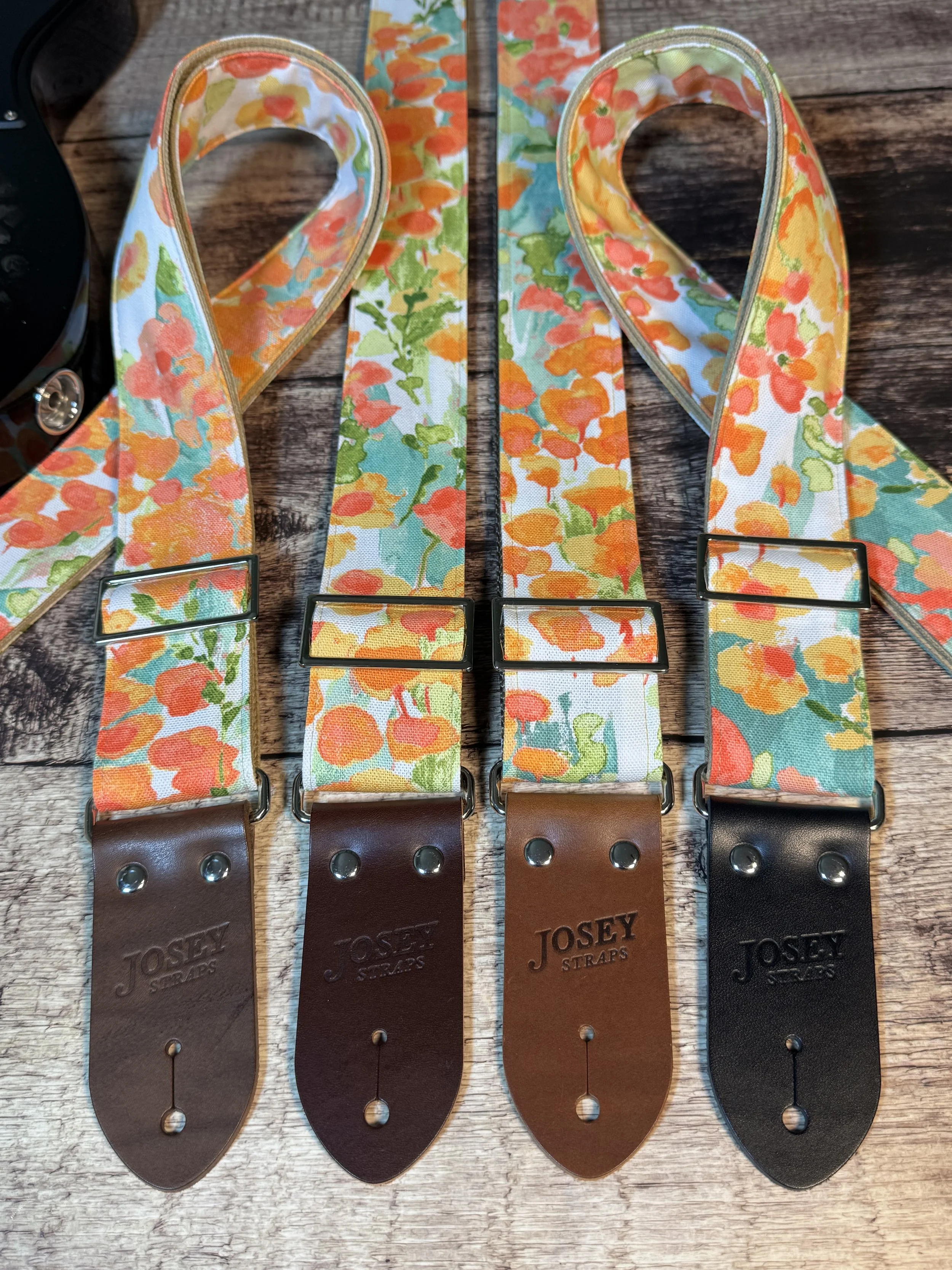 4 Floral guitar straps with orange, gold, and green flower pattern and leather ends by Josey Straps, In Bloom design