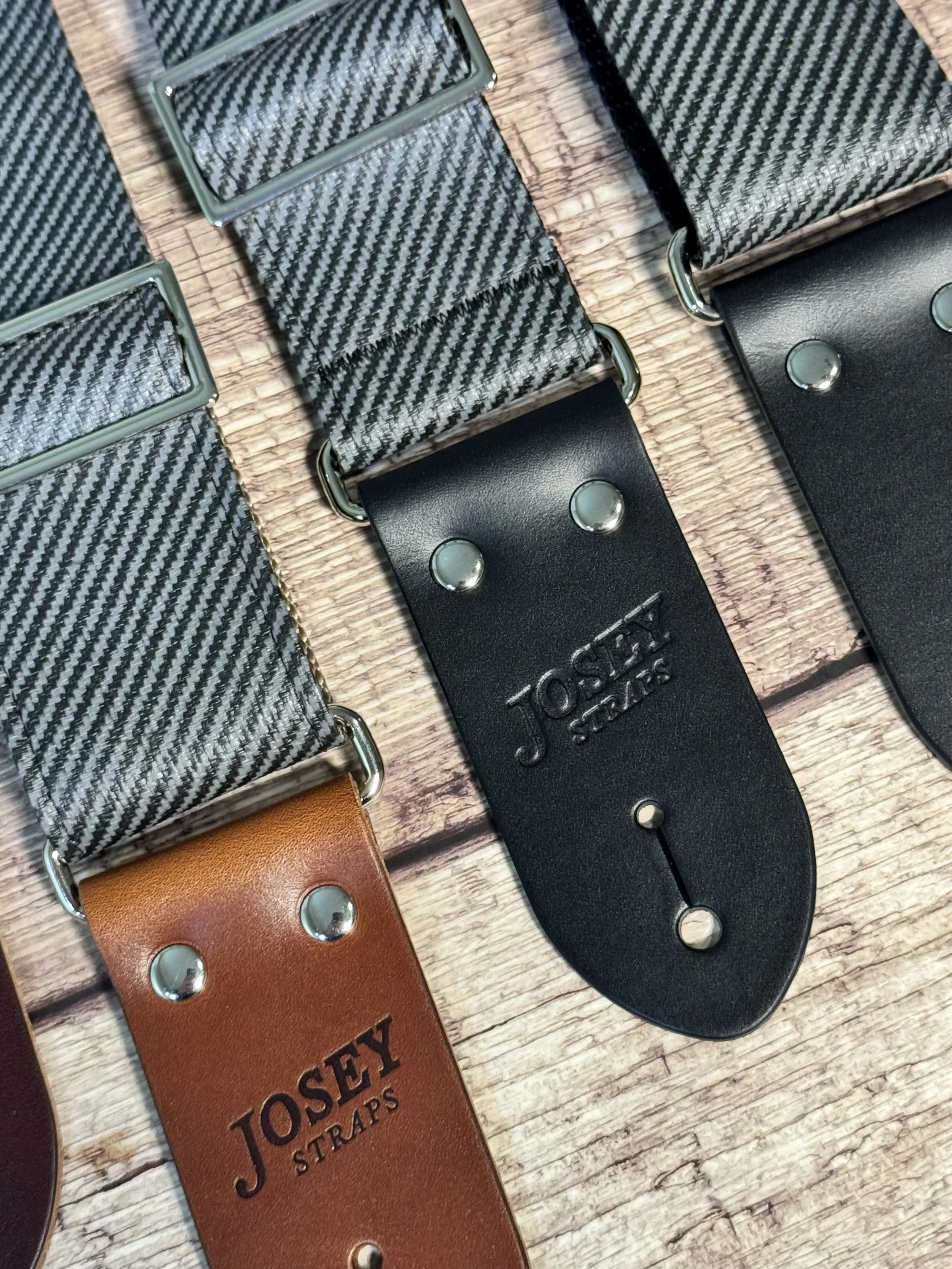 Close up shot of charcoal tweed guitar straps on wooden floor.
