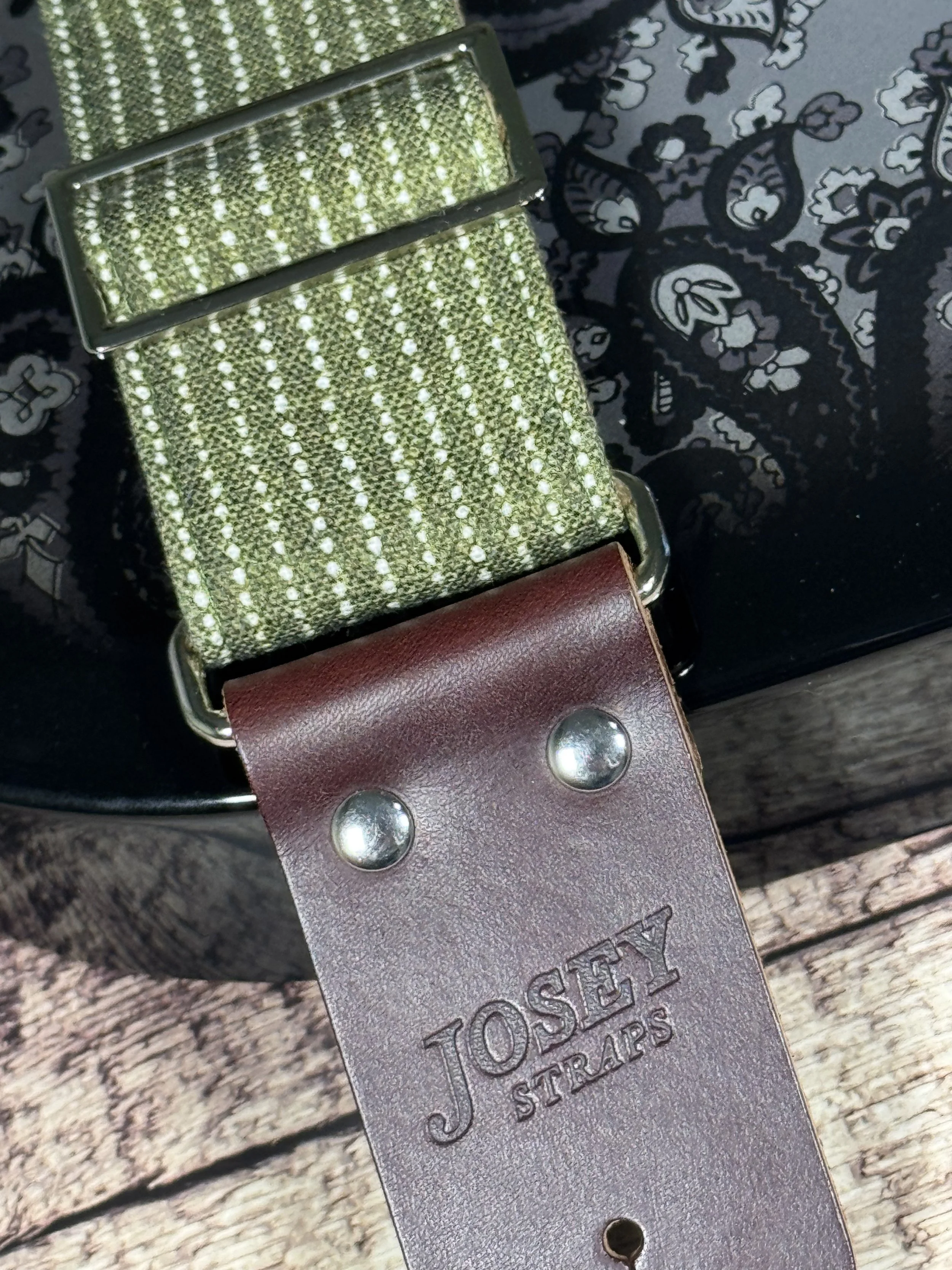 Up close photo Olive green woven guitar strap with subtle stripe pattern and leather ends by Josey Straps, Mr. Green Jeans design on black guitar