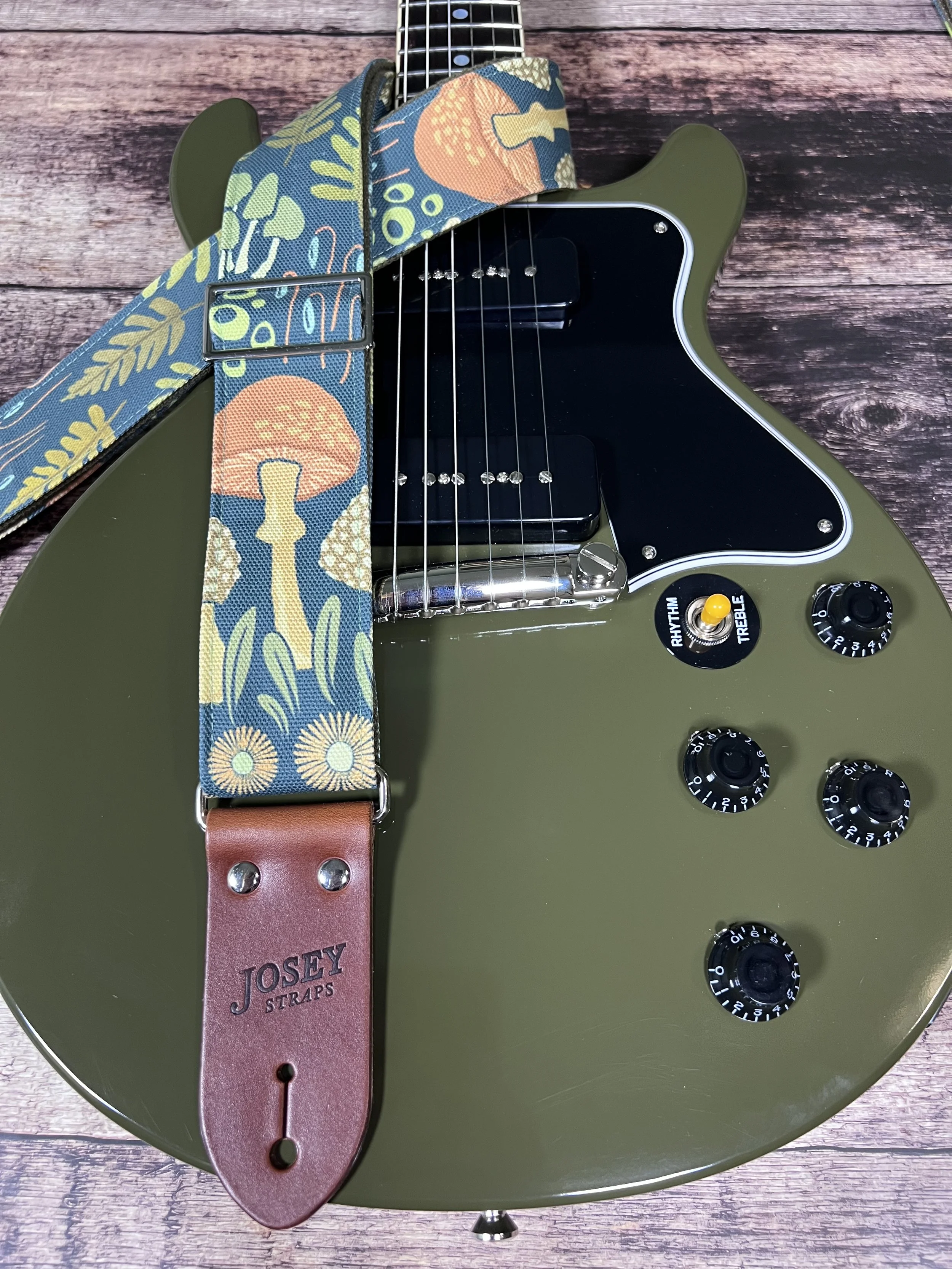 Dark botanical guitar straps on olive green guitar.