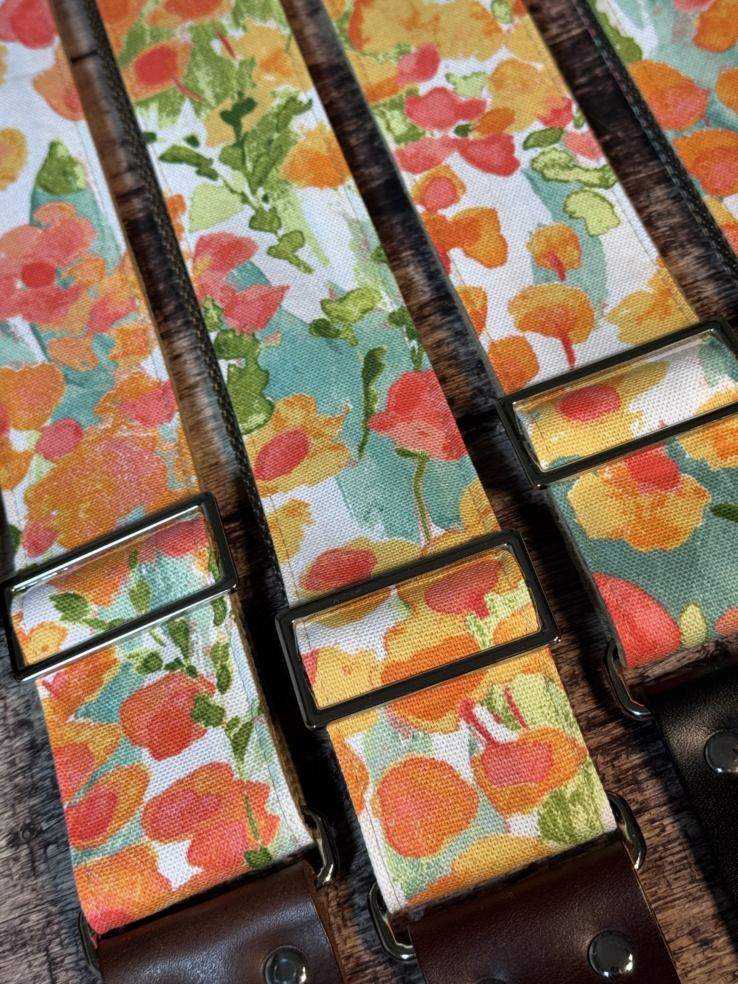 Floral guitar straps with orange, gold, and green flower pattern and leather ends by Josey Straps, In Bloom design