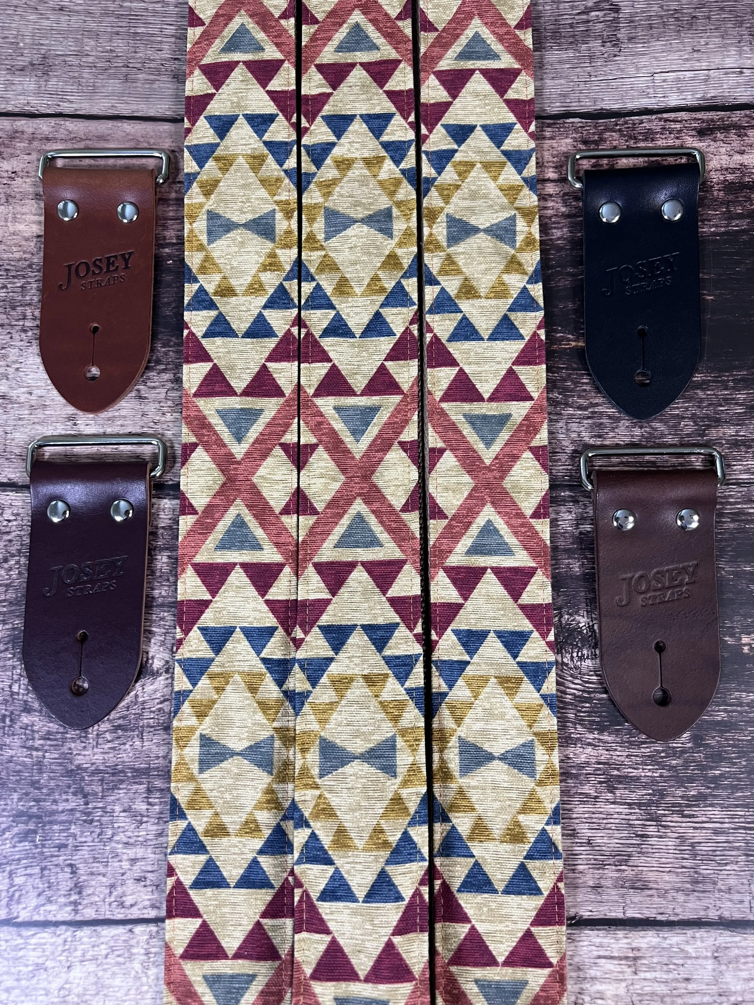 alternate photo of three guitar straps laid out on wood background showing leather end options