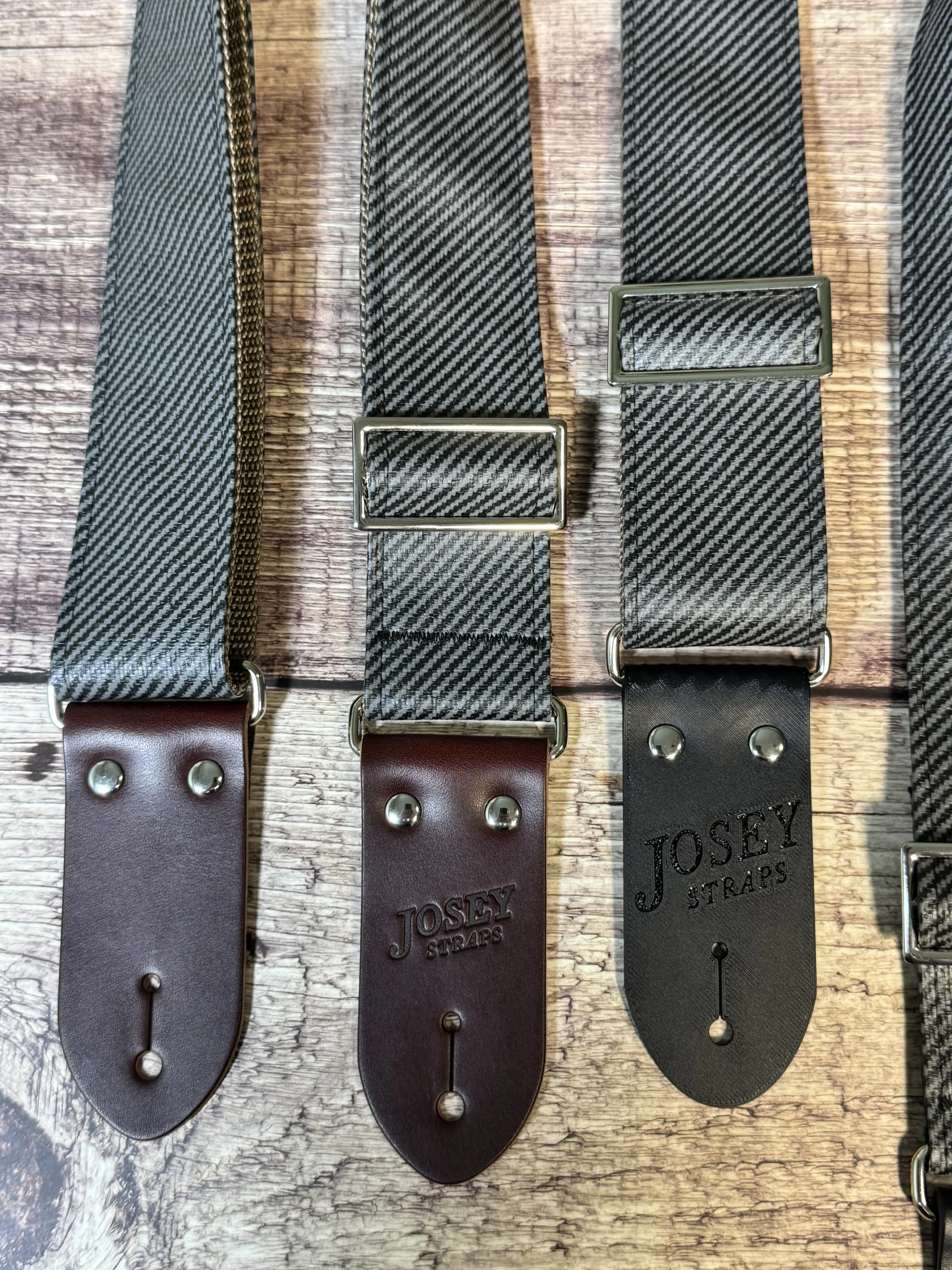 Charcoal tweed guitar straps on wooden floor.