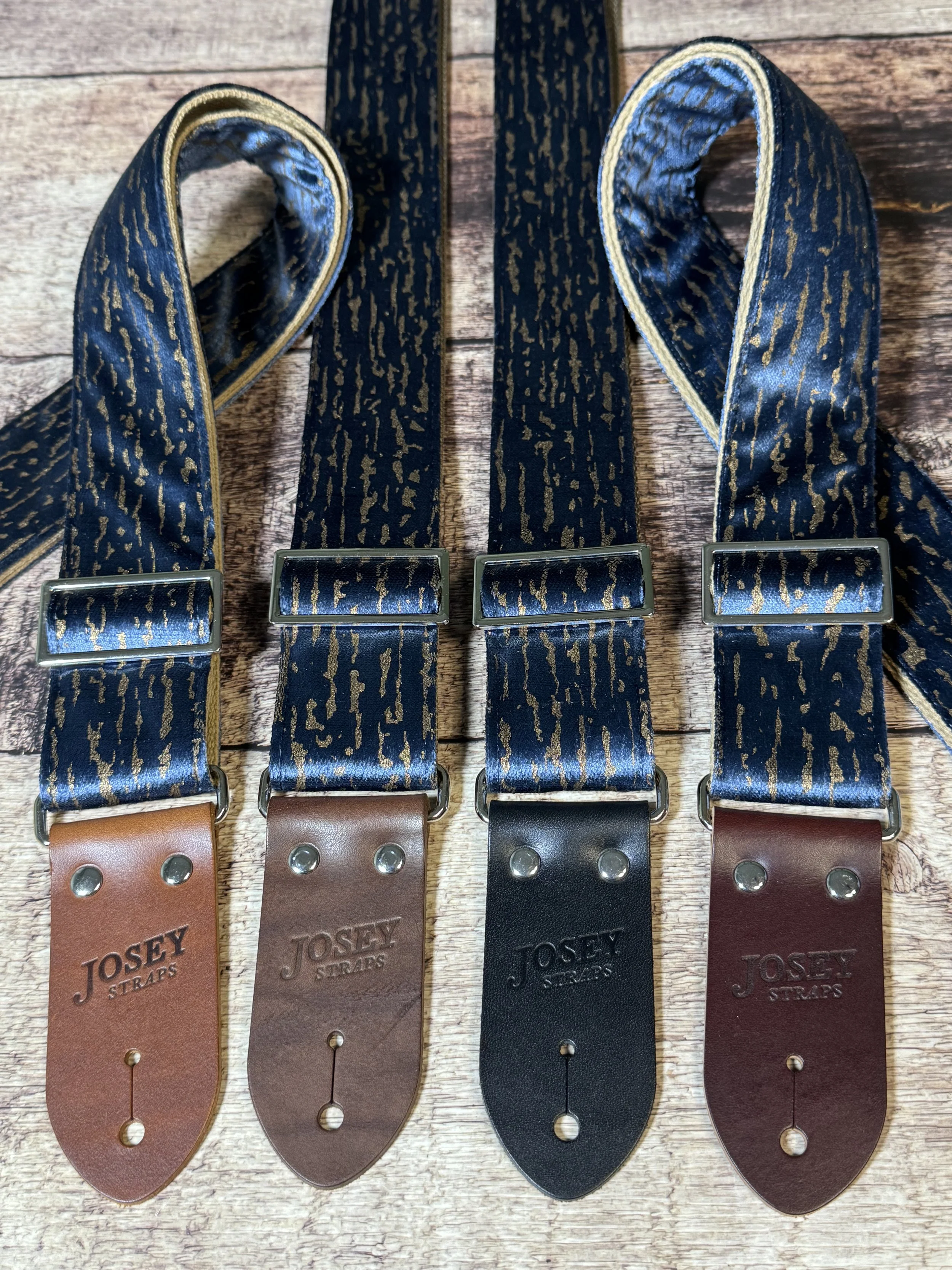 Blue and gold guitar straps on a wooden floor backdrop.