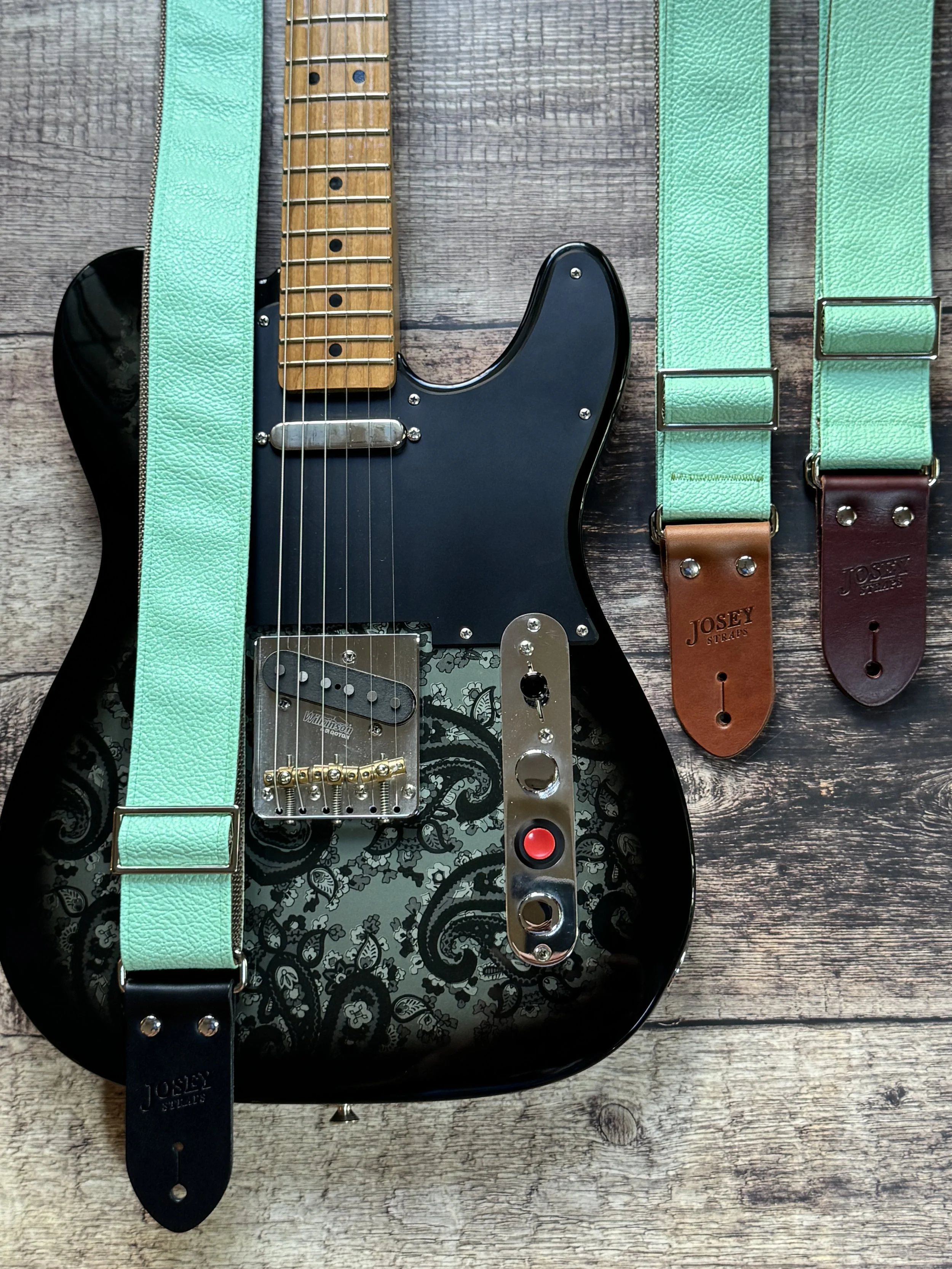 Seafoam green guitar strap on black guitar.
