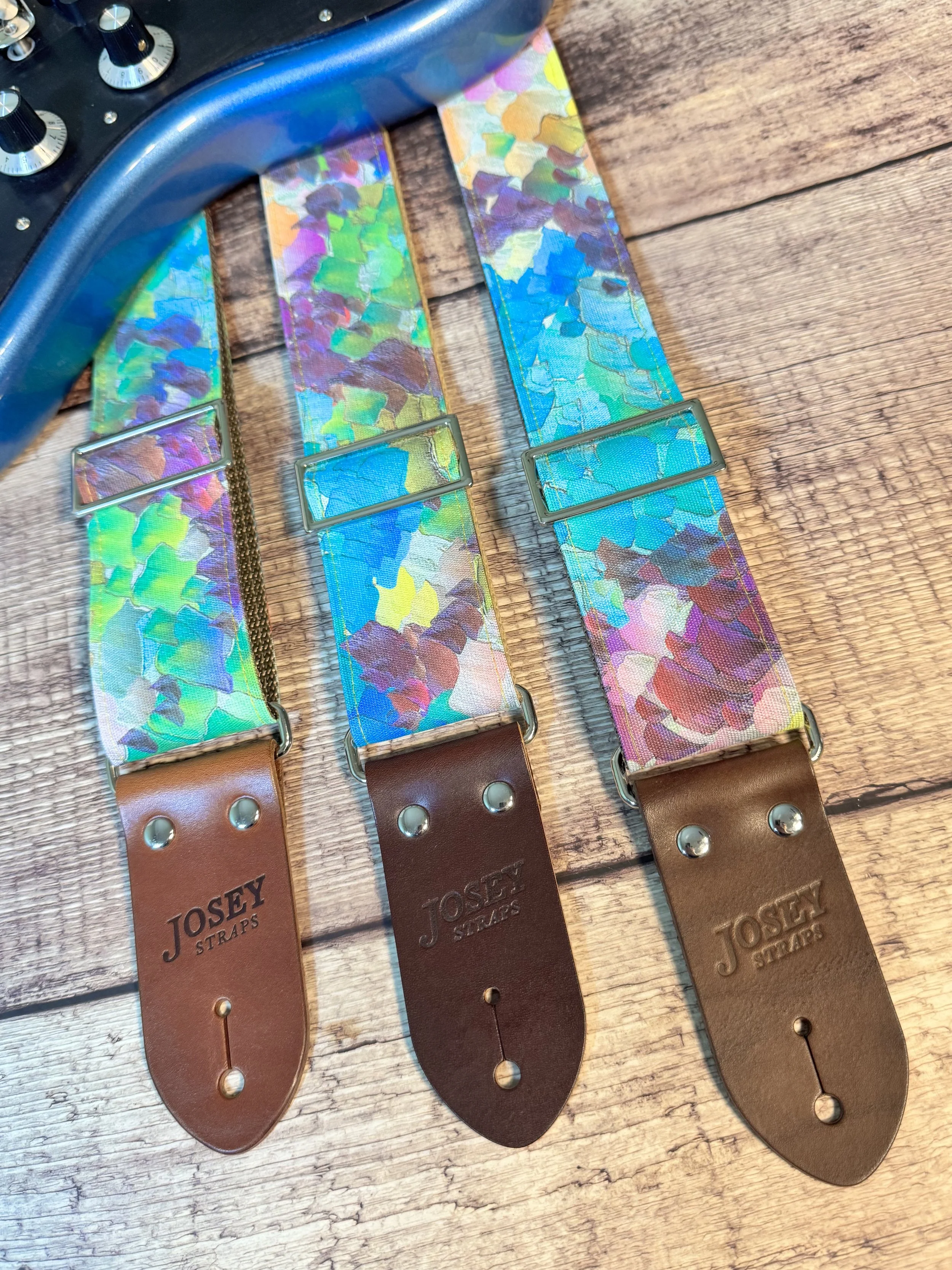 Impasto handmade guitar strap by Josey Straps featuring a vibrant abstract painterly pattern in blue, green, purple, and yellow with premium leather ends.