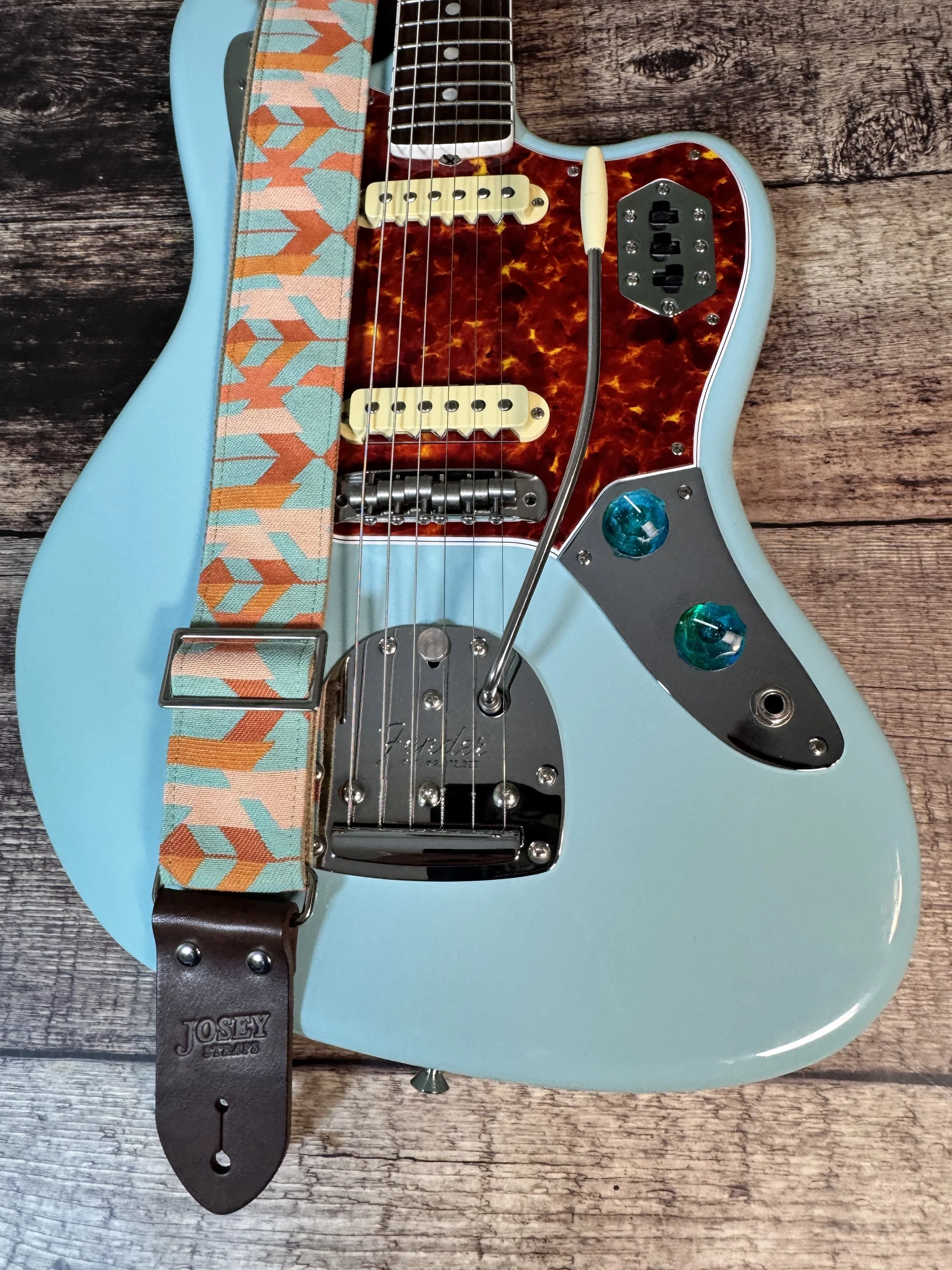 Mesa Verde handmade guitar strap by Josey Straps featuring a geometric Southwestern-inspired pattern in turquoise, terracotta, orange, and cream with premium leather ends.