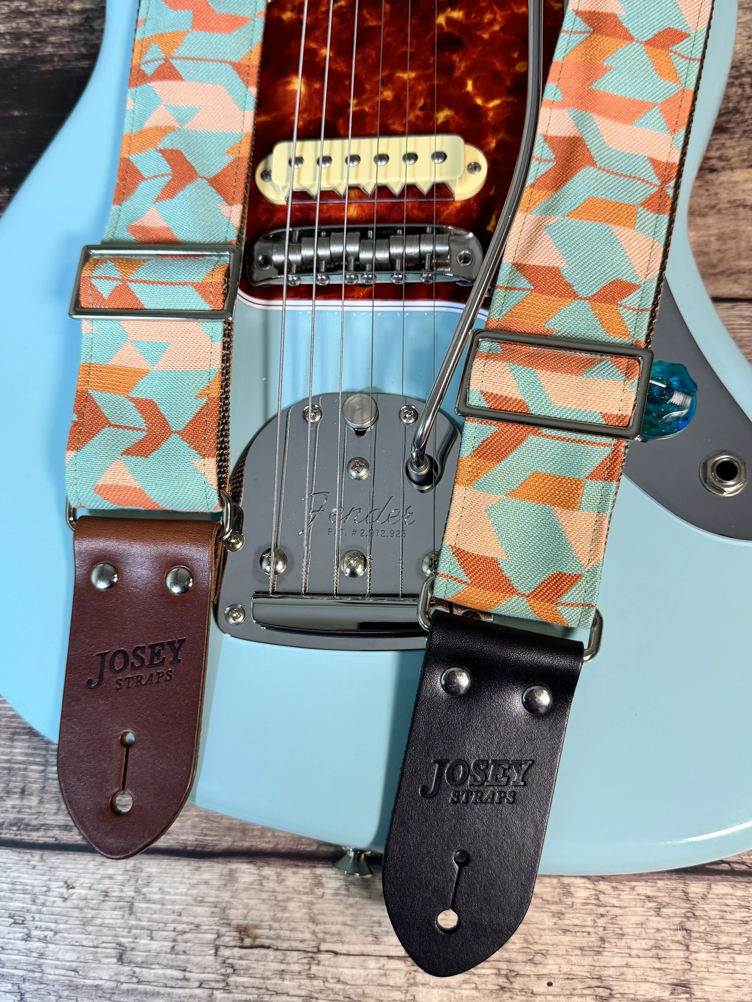 Mesa Verde handmade guitar strap by Josey Straps featuring a geometric Southwestern-inspired pattern in turquoise, terracotta, orange, and cream with premium leather ends.