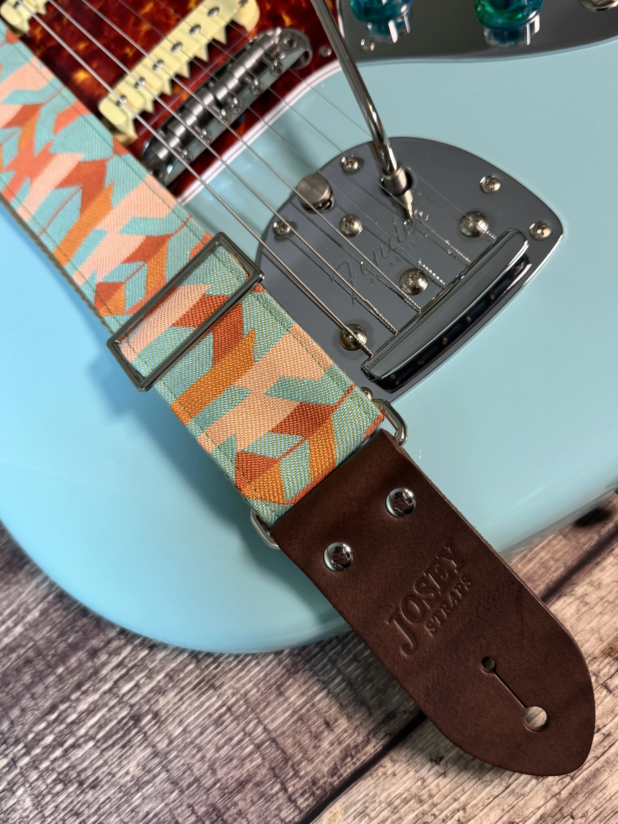 Mesa Verde handmade guitar strap by Josey Straps featuring a geometric Southwestern-inspired pattern in turquoise, terracotta, orange, and cream with premium leather ends.