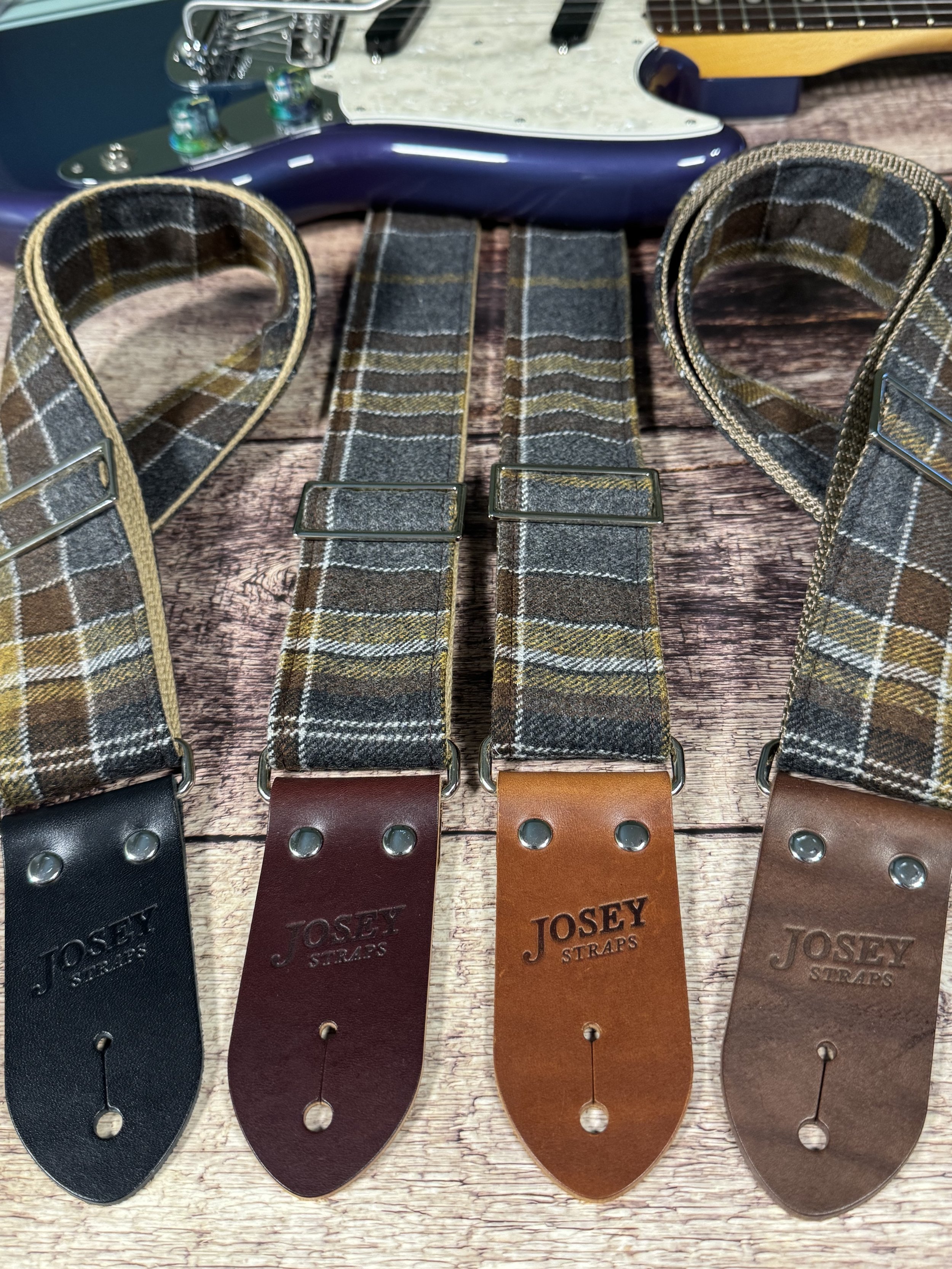 Ashes plaid guitar strap with leather ends by Josey Straps displayed on wood background