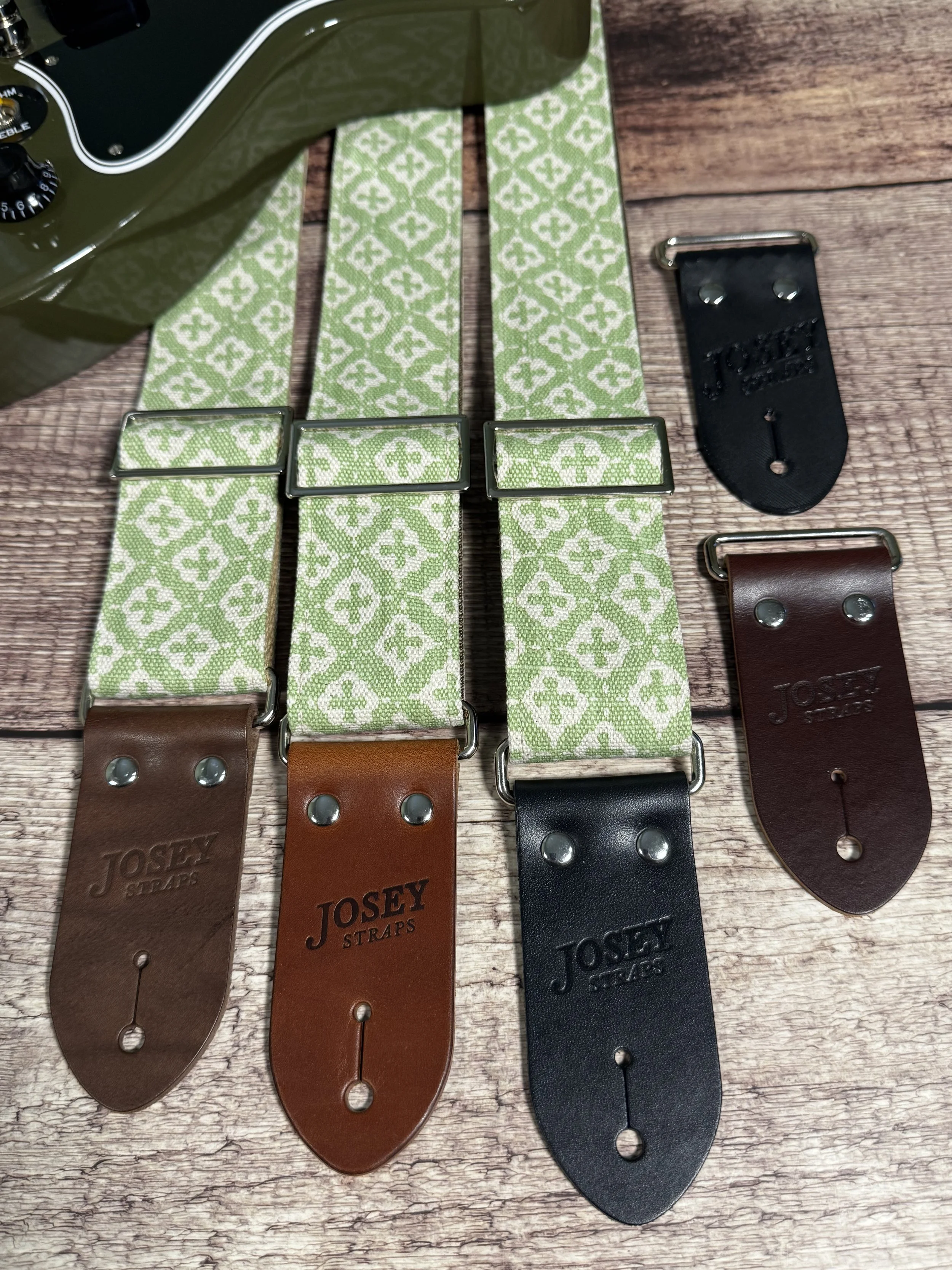 The Green House handmade guitar strap by Josey Straps featuring a sage green and cream geometric pattern with premium leather ends.