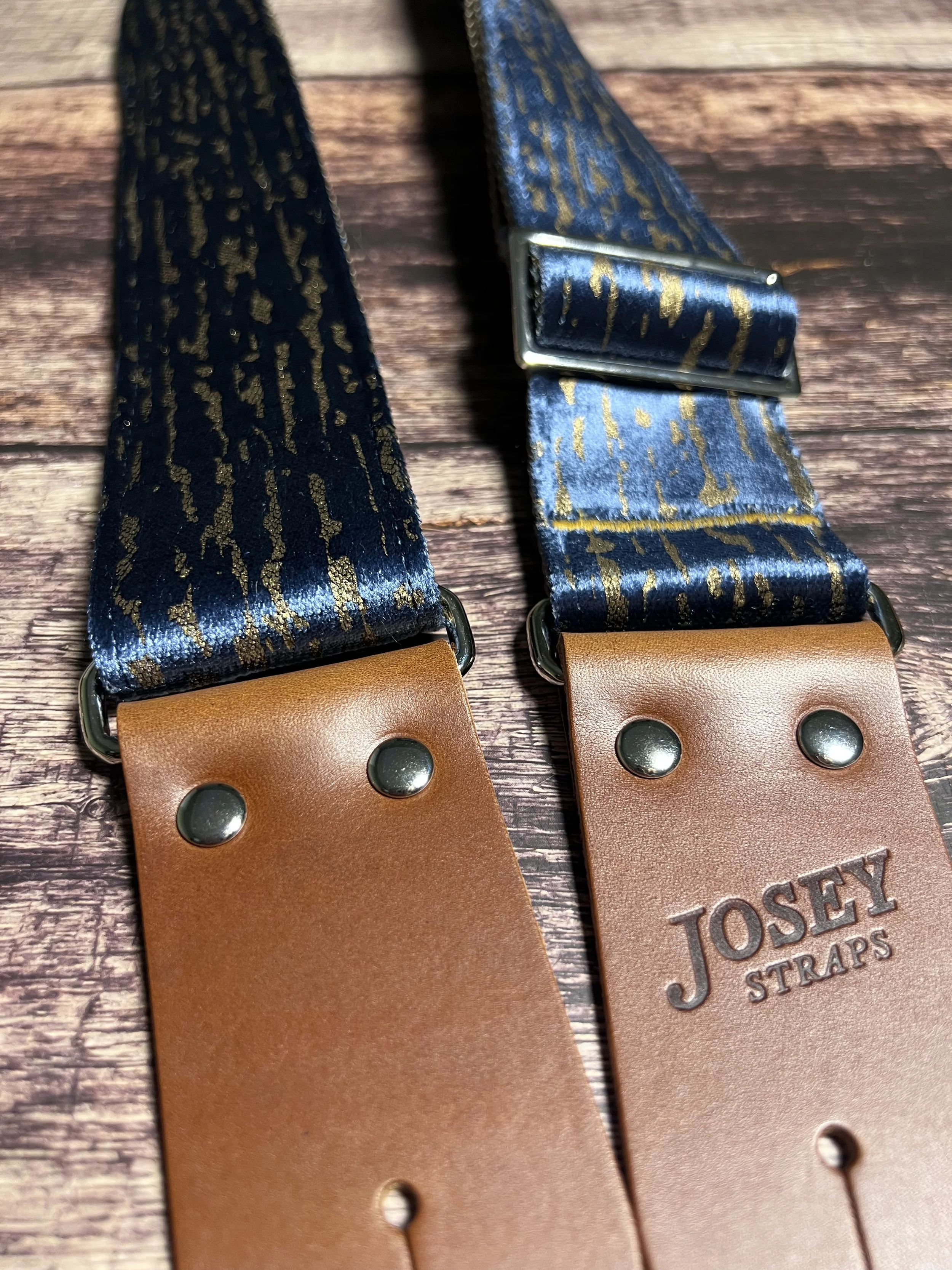 Blue and gold guitar strap on wooden floor.