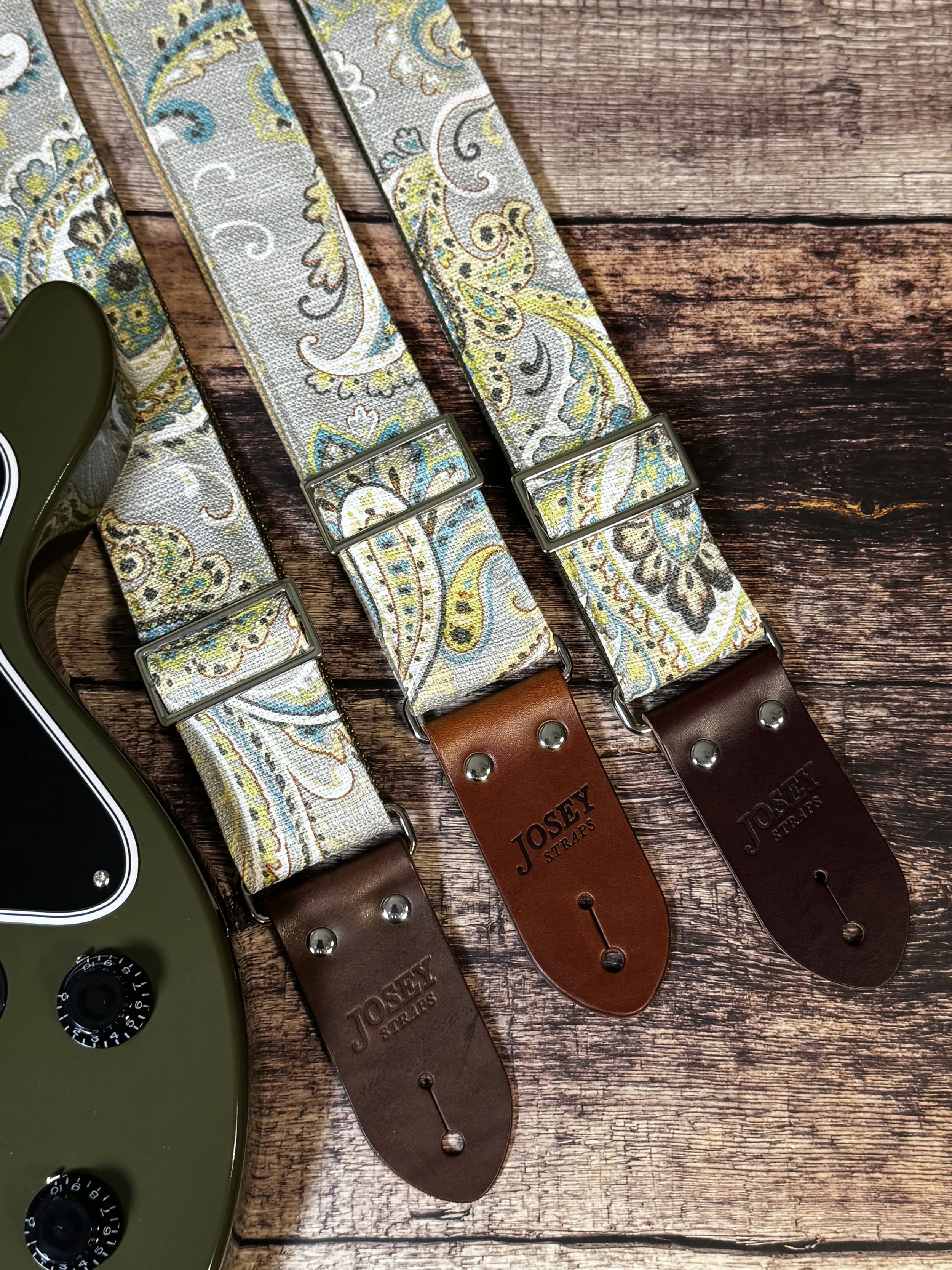 Graisley handmade paisley guitar strap featuring a gray, cream, blue, and mustard vintage-inspired pattern with premium leather ends.