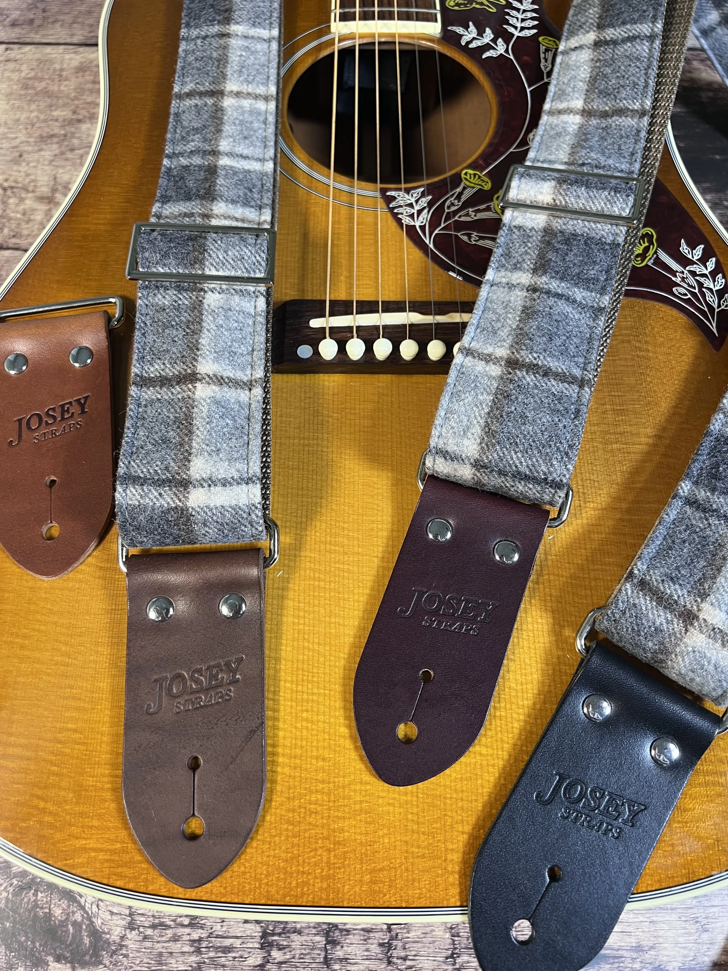 Vintage style grey plaid guitar straps on acoustic guitar.