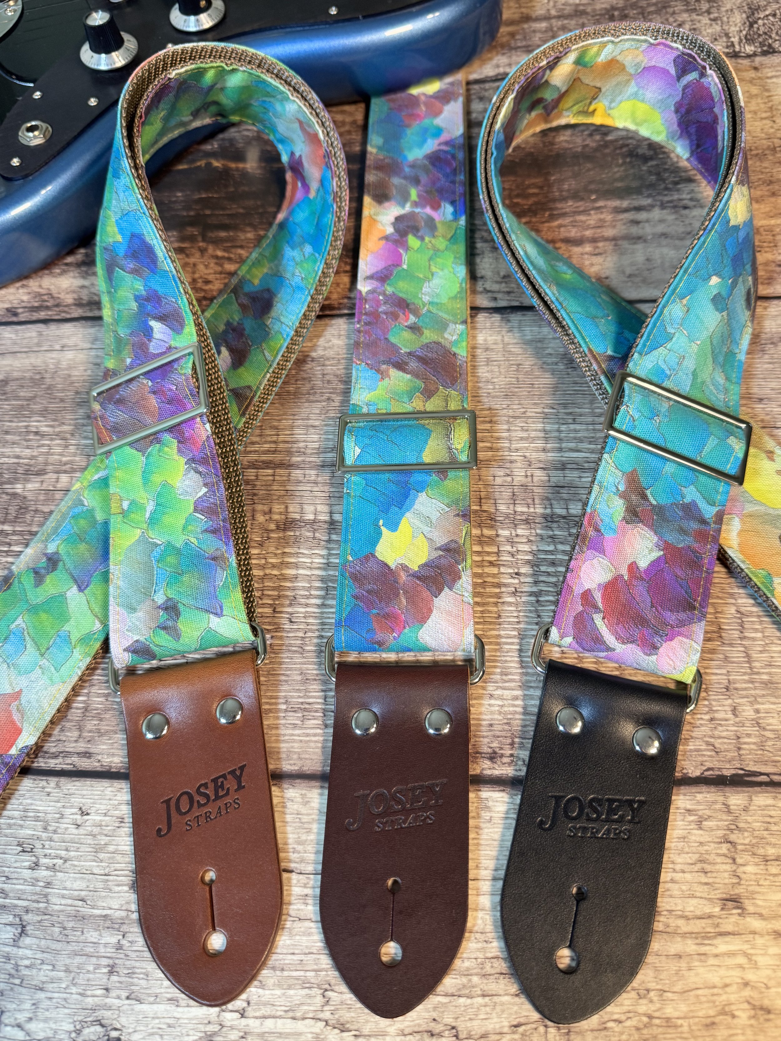 Impasto handmade guitar strap by Josey Straps featuring a vibrant abstract painterly pattern in blue, green, purple, and yellow with premium leather ends.