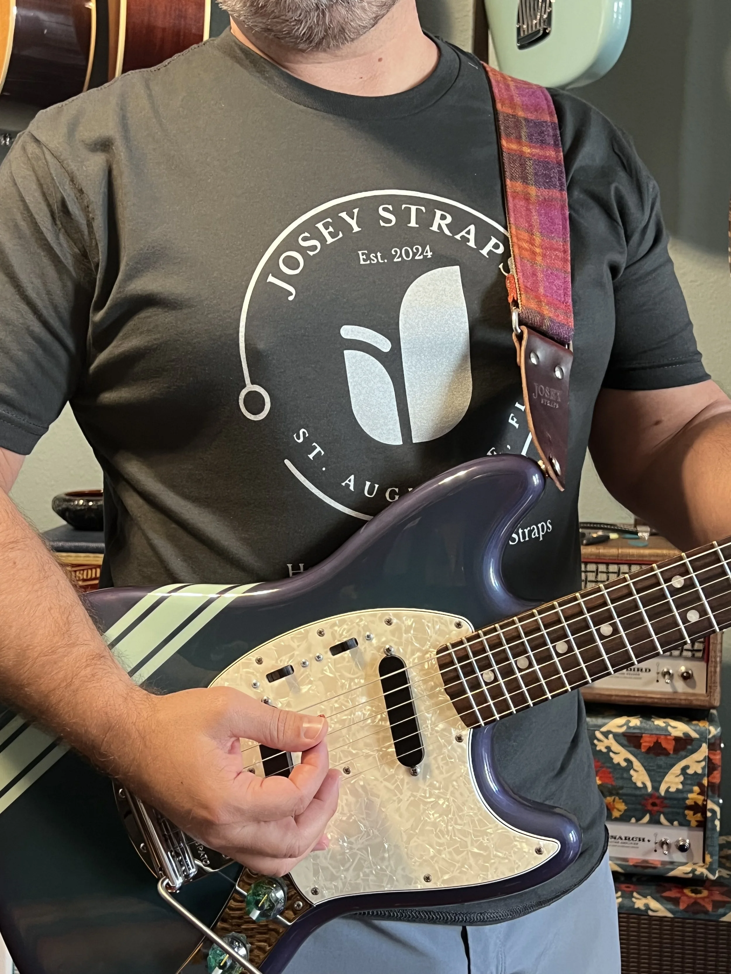 Male model wearing a Josey Straps vintage black screen printed t-shirt while playing guitar.