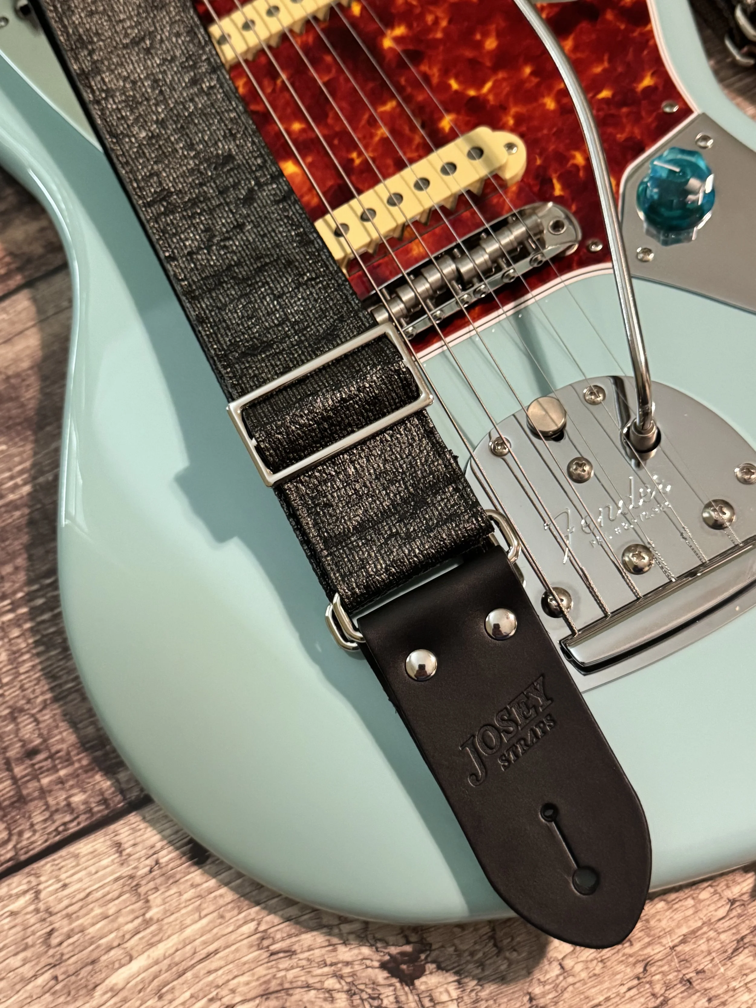 Pewter Slub guitar strap on on top of a blue guitar.
